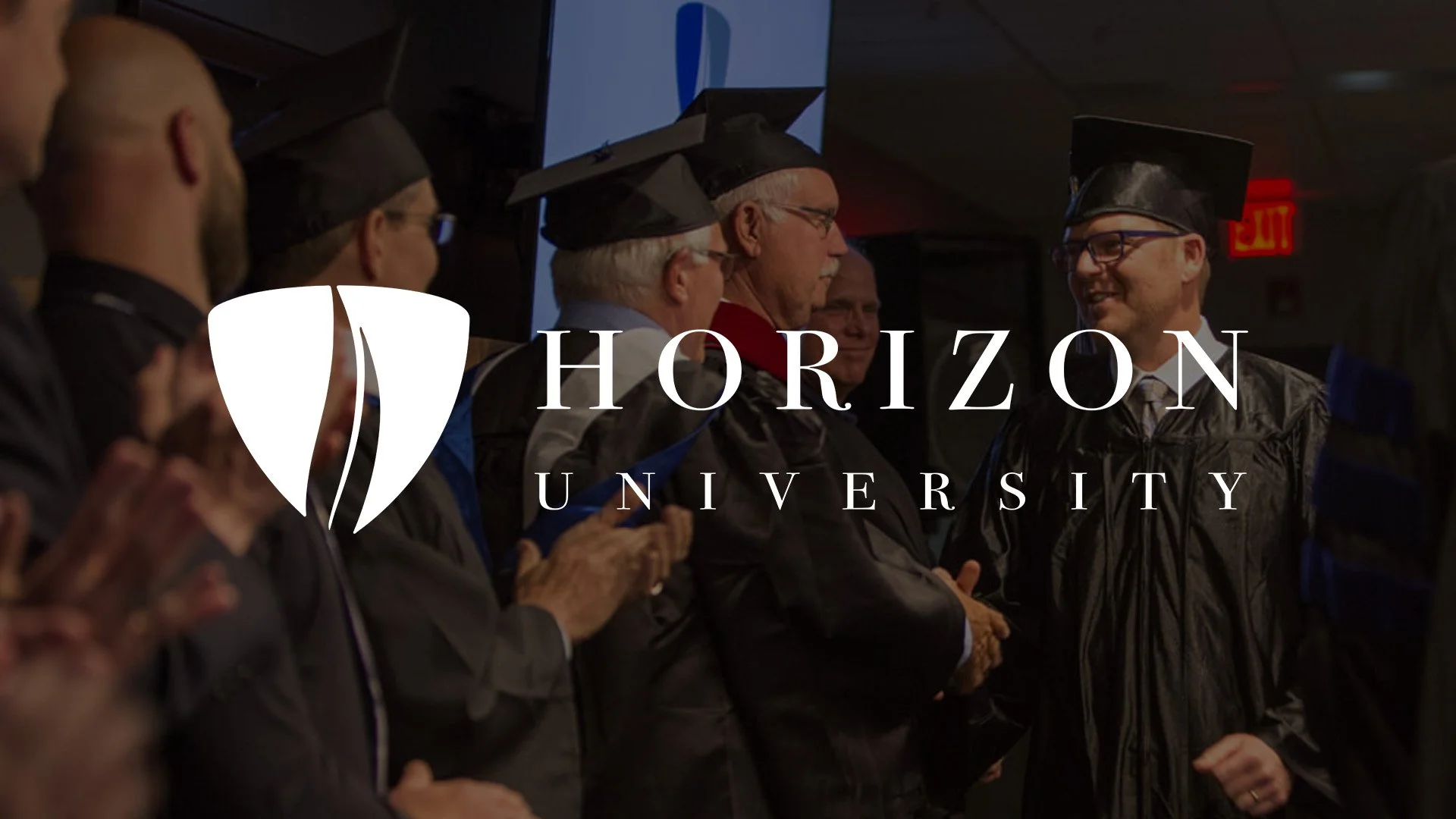 Graduation ceremony at Horizon University with faculty and graduates in caps and gowns, some clapping and smiling.