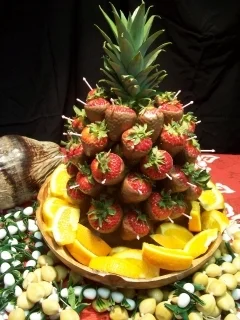 STRAWBERRY/PINEAPPLE DISPLAY Large, ripe strawberries are double dipped in white chocolate and individually arranged on a full pineapple display. A beautiful addition for tropical buffets or use as table centerpieces. 32-40 strawberries per arrangement. Each arrangement, $90