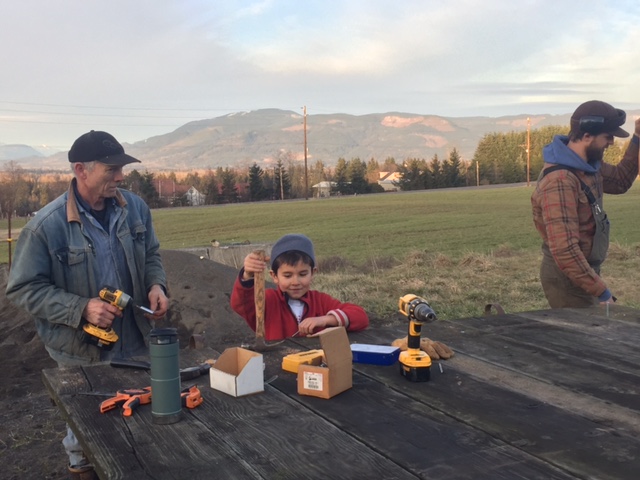 Myrle, Ramone and Matthew attach floorboards to a metal sled base that Myrle and his family used to use for pig housing. 