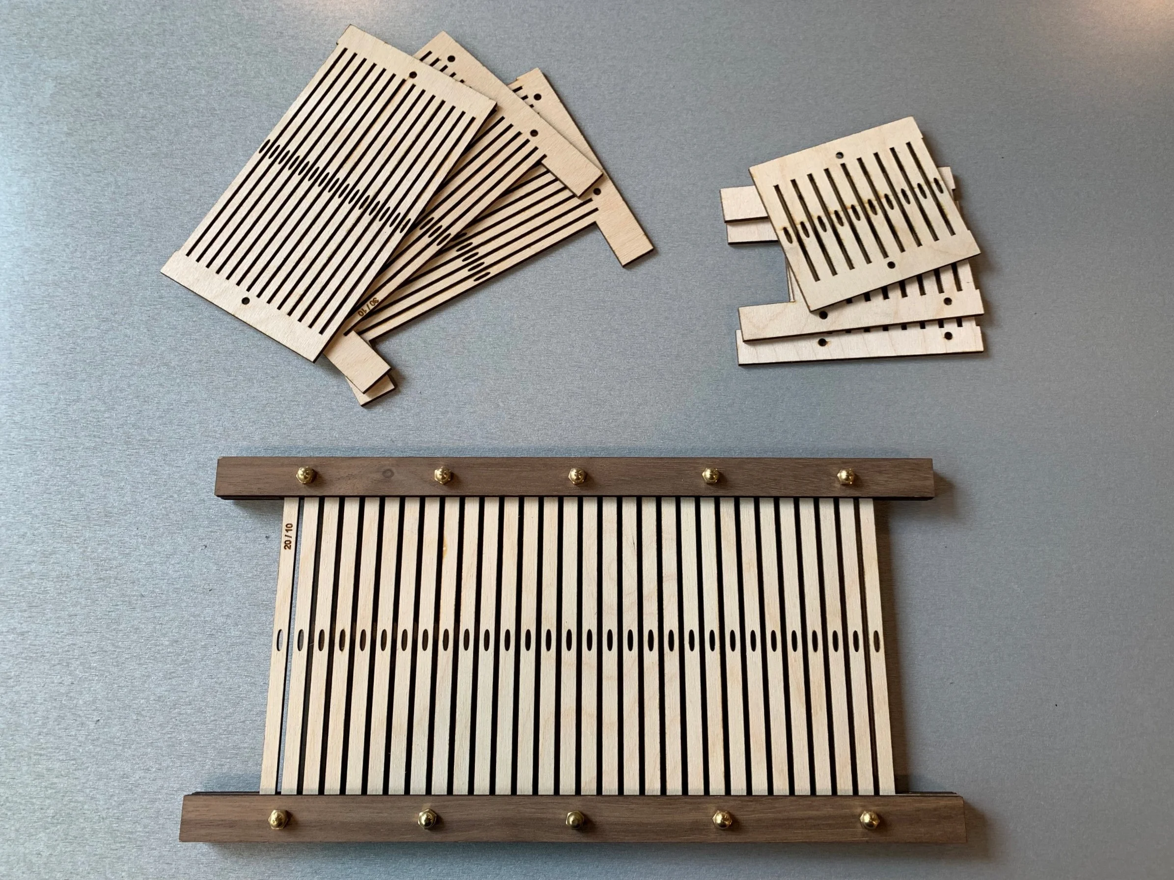 My loom accommodates a 30cm wide heddle, which I designed in 3 separate pieces that are sandwiched between top and bottom bars, fastened with some stock parts. The heddle can be easily taken apart to insert reeds with different dent ratios.