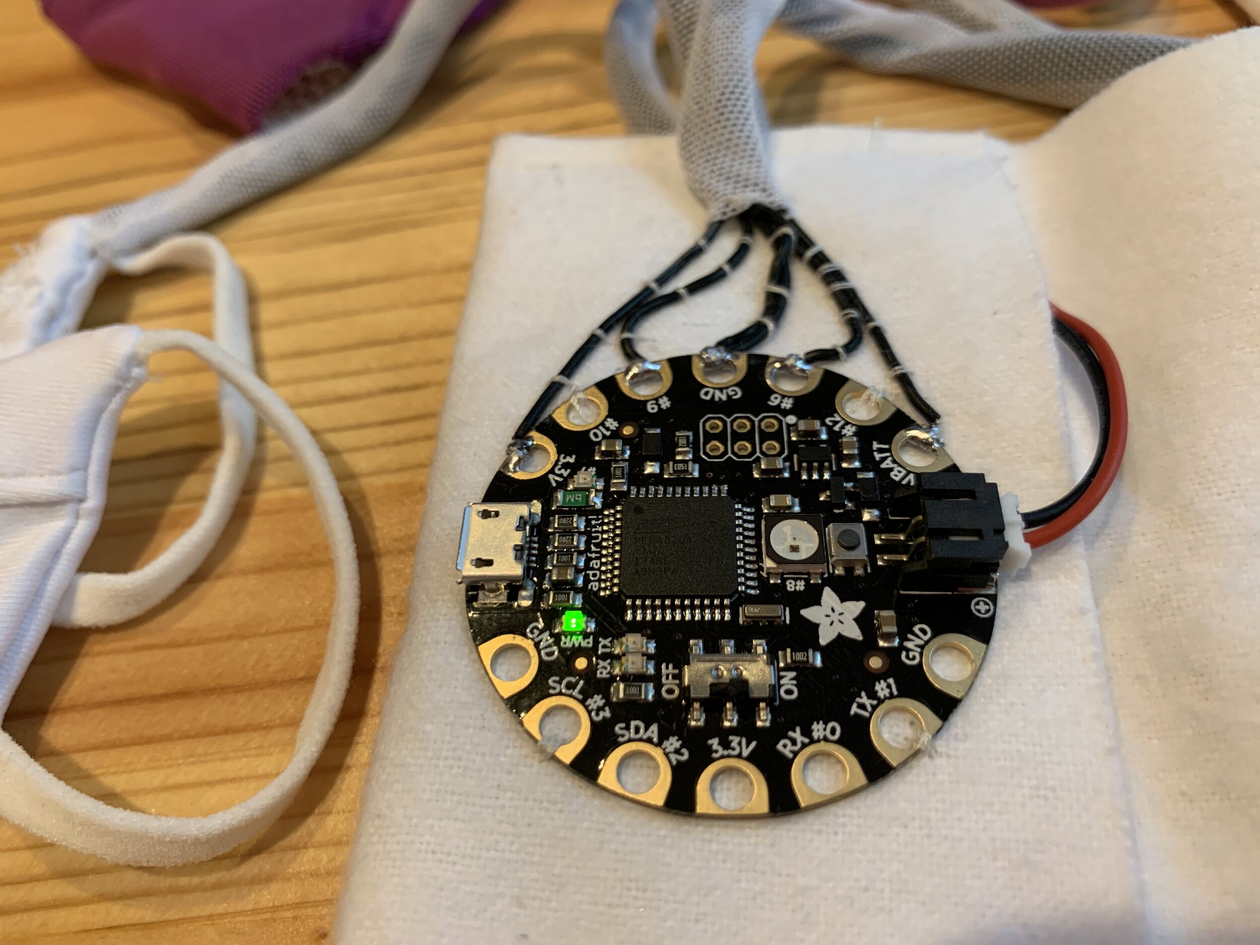 The Adafruit Flora microcontroller in its pocket, with rechargeable LiPo battery