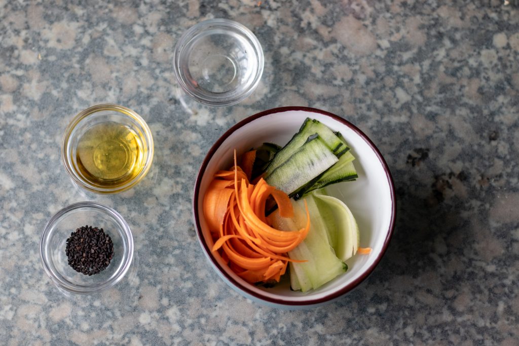 Ahora coloca los vegetales en un tazón e incorpora el vinagre de arroz, el mirin, el aceite de sésamo y las semillas.
