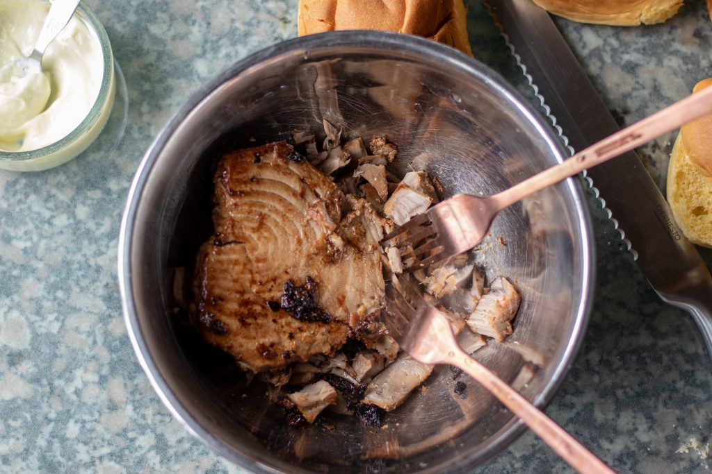 Lleva el atún cocido y los trozos de adobo sobrantes a un tazón y tritúralo en trozos grandes con un par de tenedores.