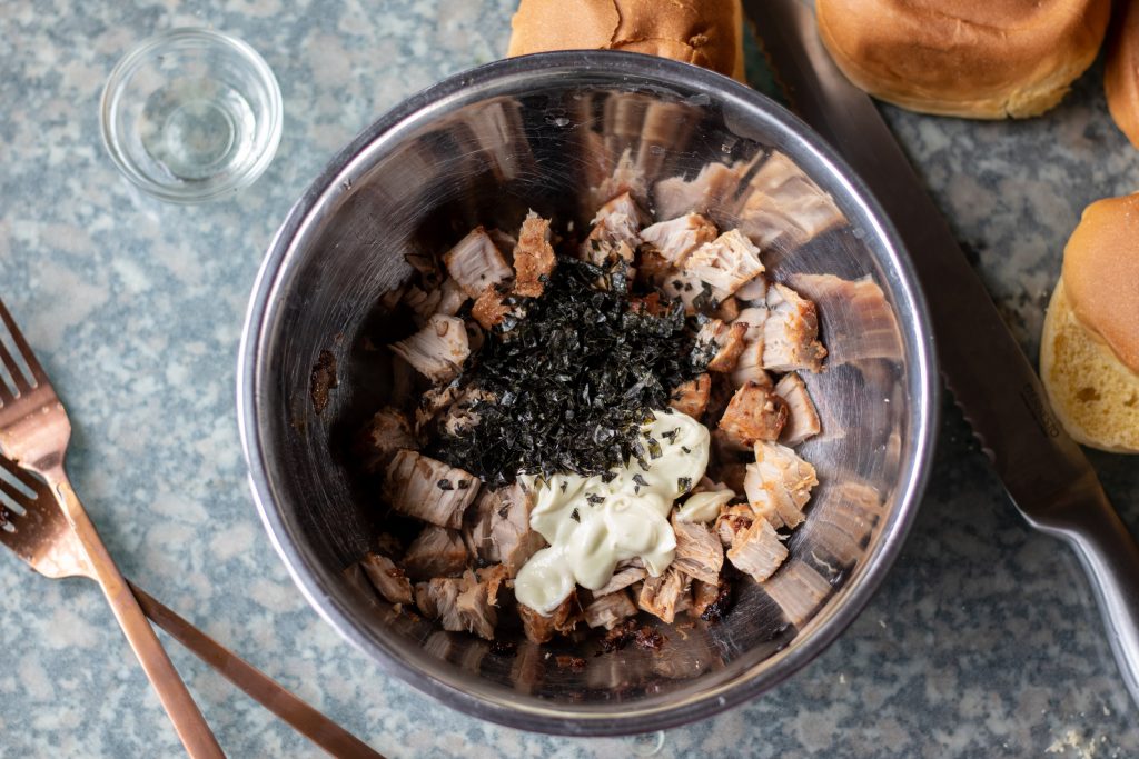 Agrega la mayonesa de wasabi y el nori tostado al tazón con el atún y mezcla bien para combinar y distribuir uniformemente la salsa y las hojuelas en todo el atún.