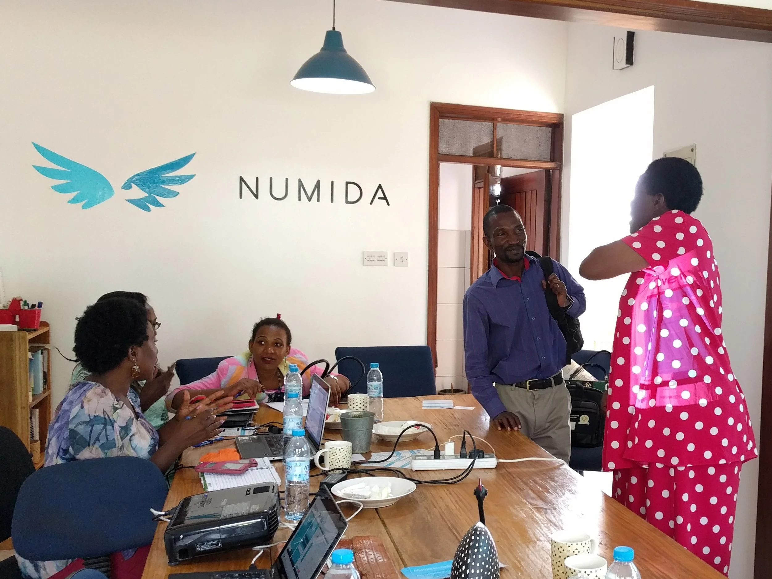 Entrepreneurs and staff members talk inside the Numida office in Kampala, Uganda.