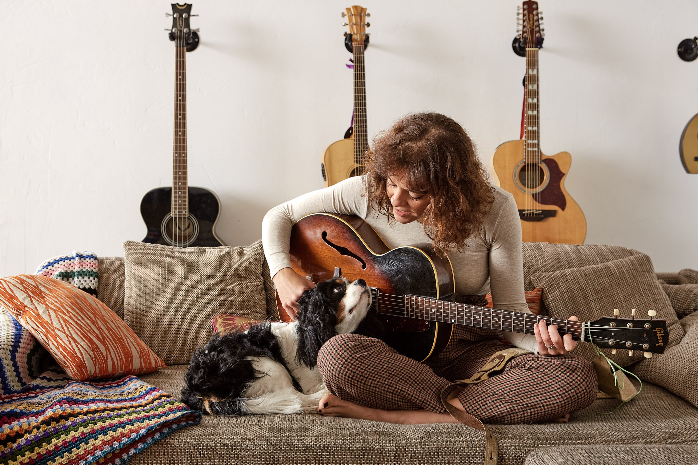 Adaptil portrait of a woman playing a guitar with her dog next to her.
