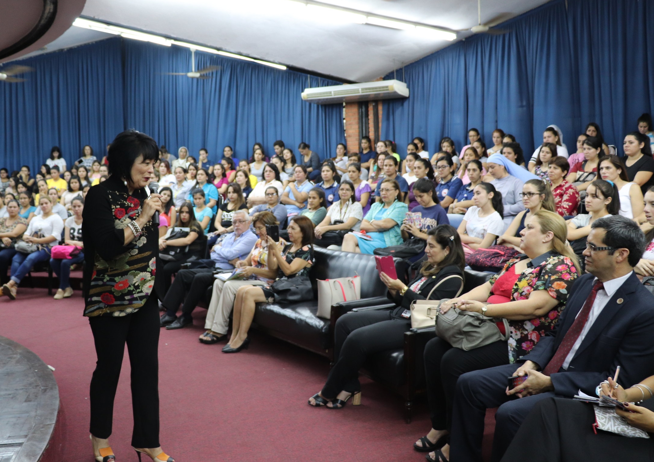 Image of a female Specialist with chin-length black hair speaking to an audience using a microphone.