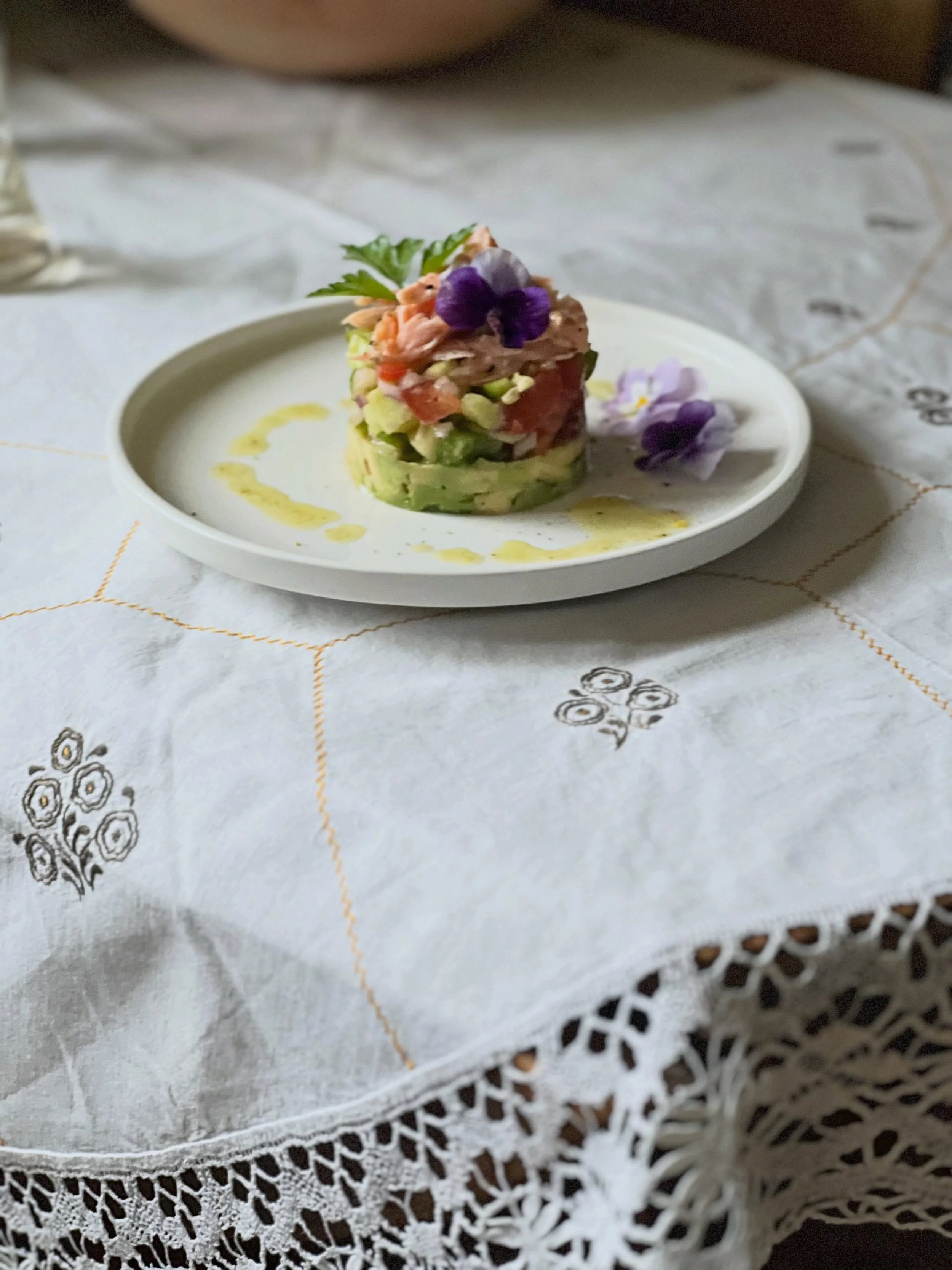 A simple salmon tartare, dressed for summer with fresh vegetables, edible flowers, and a light lemon vinaigrette. Served on vintage linens at Heimgar, where even the smallest meals become little celebrations.

&bull;
#heimgar #salmontartare #summerta