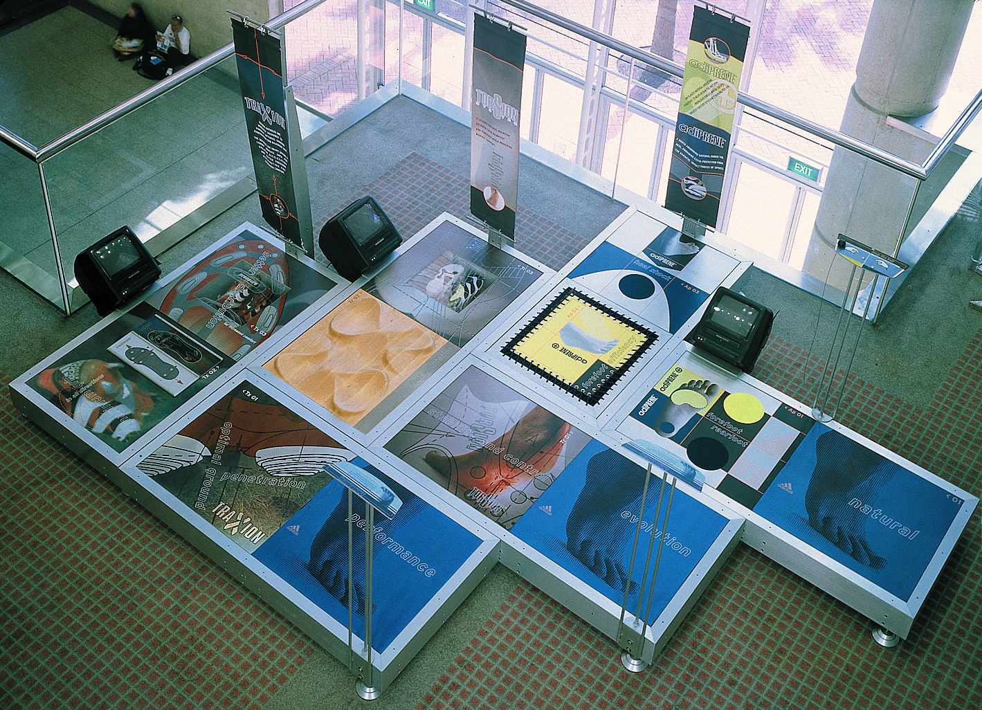 T he challenge presented to A/D by Adidas International was to create a traveling interactive experience which would effectively communicate the “feet you wear” design philosophy, technology and benefits to a diverse audience. Our approach to this problem was to create a “feet on” interactive experience which would serve to inspire the individual to think more about their feet and how they interact with various terrain. A modular frame floor system was developed which induced the participant to remove their shoes in order to fully interact with the experience. Each technology (traction, torsion, cushioning) was abstractly translated into a sensory experience. Additionally, the design incorporated DVD/video and vertical banner elements which further enhanced and explained FYW technology creating even greater impact and understanding.