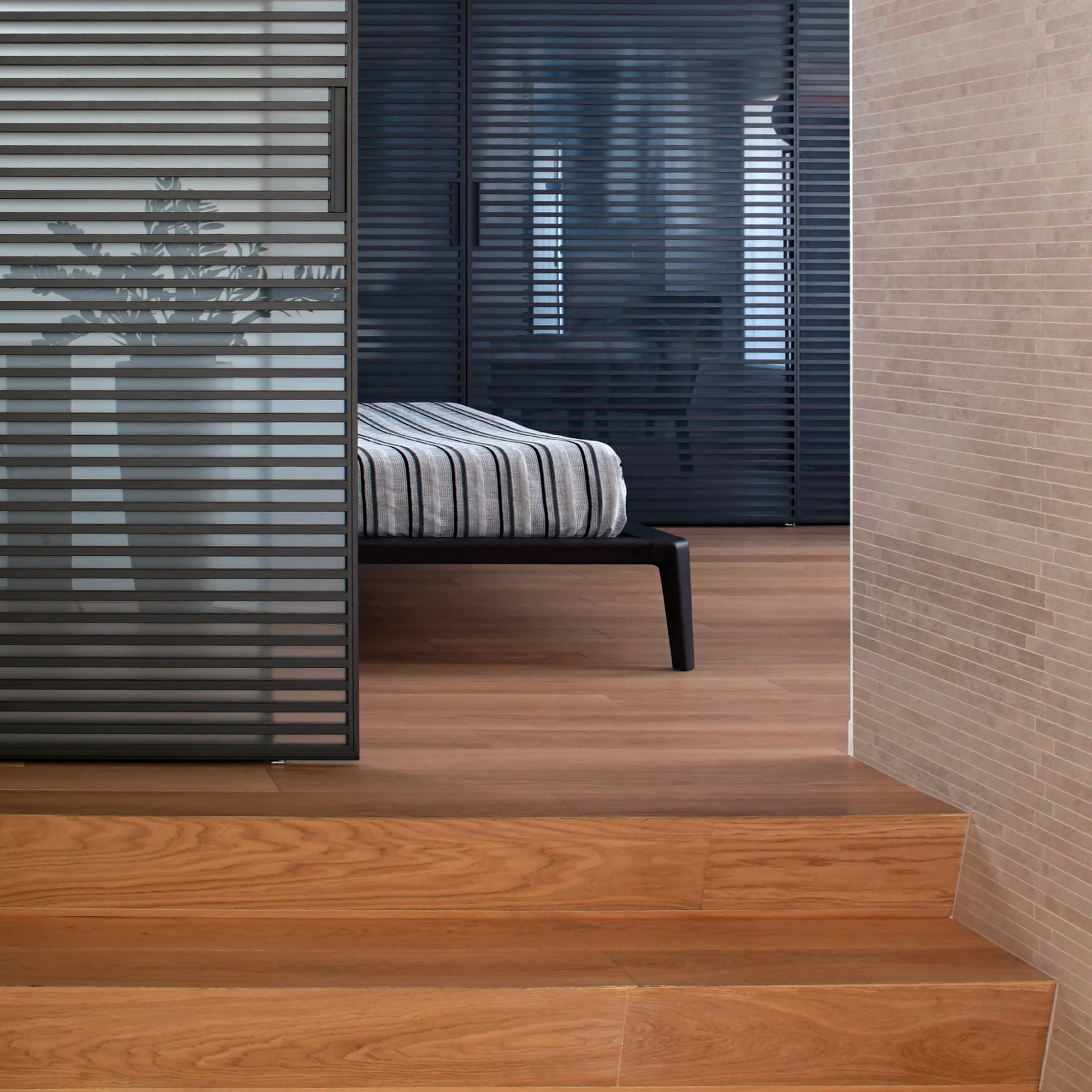 Dettaglio del livello rialzato con gradini in parquet di rovere, pannello scorrevole Rimadesio e parete in mattone a vista — Attico a doppia altezza, Parma