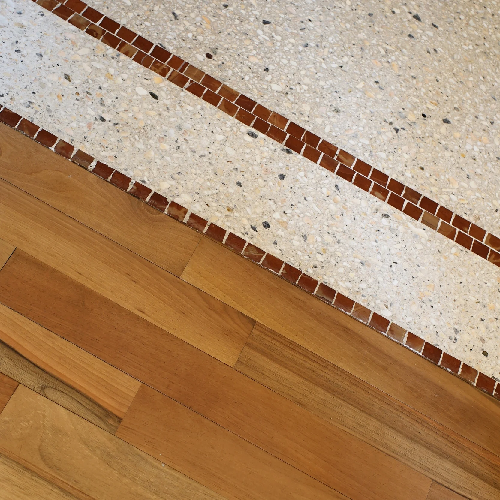 Dettaglio della giunzione tra seminato alla veneziana con listello in mosaico e parquet — Una casa milanese, Milano.jpg
