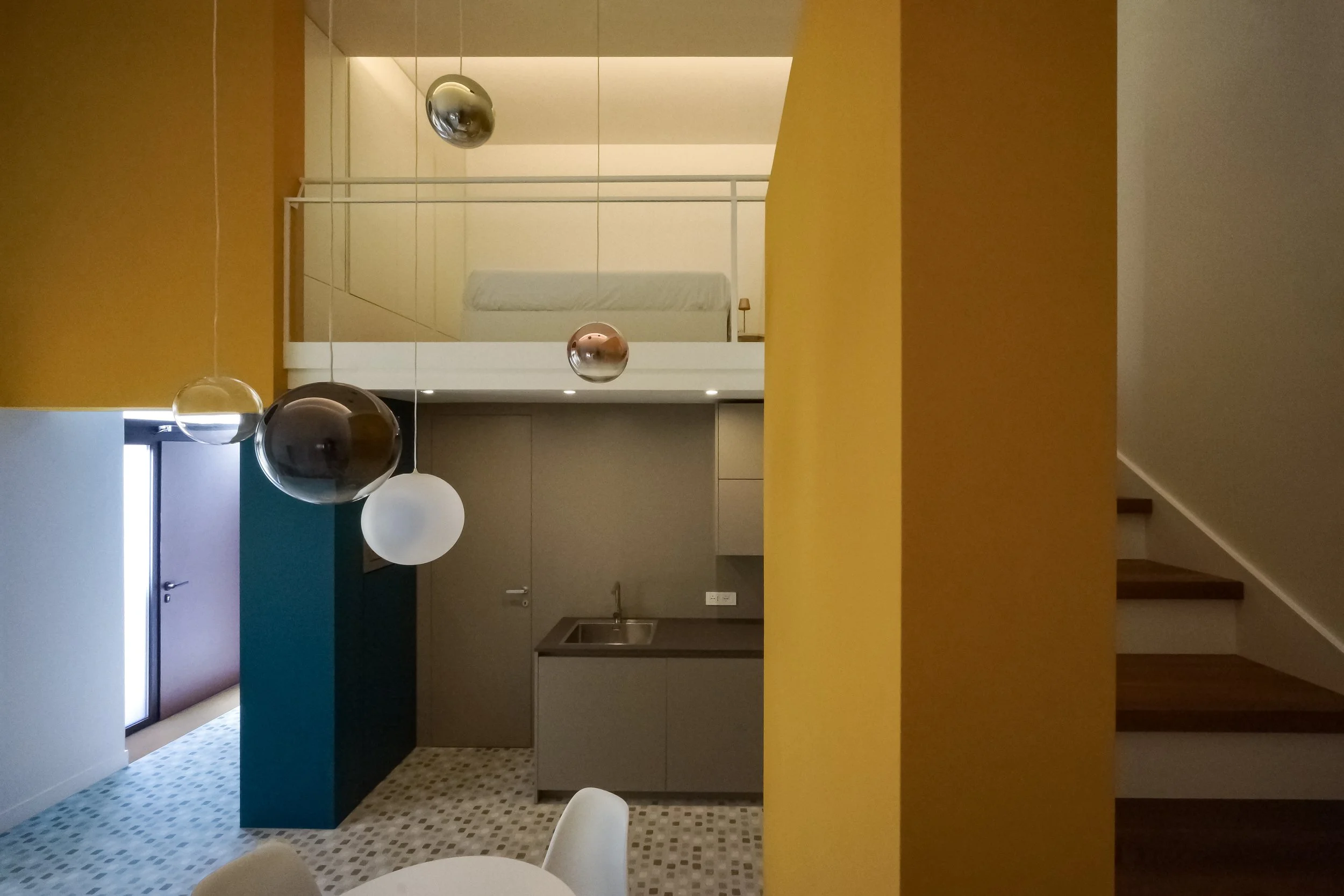 Vista generale della zona giorno con soppalco, angolo cottura, setti colorati e in primo piano i corpi illuminanti della serie Random Solo di Lodes, Farina Loft, Cagliari