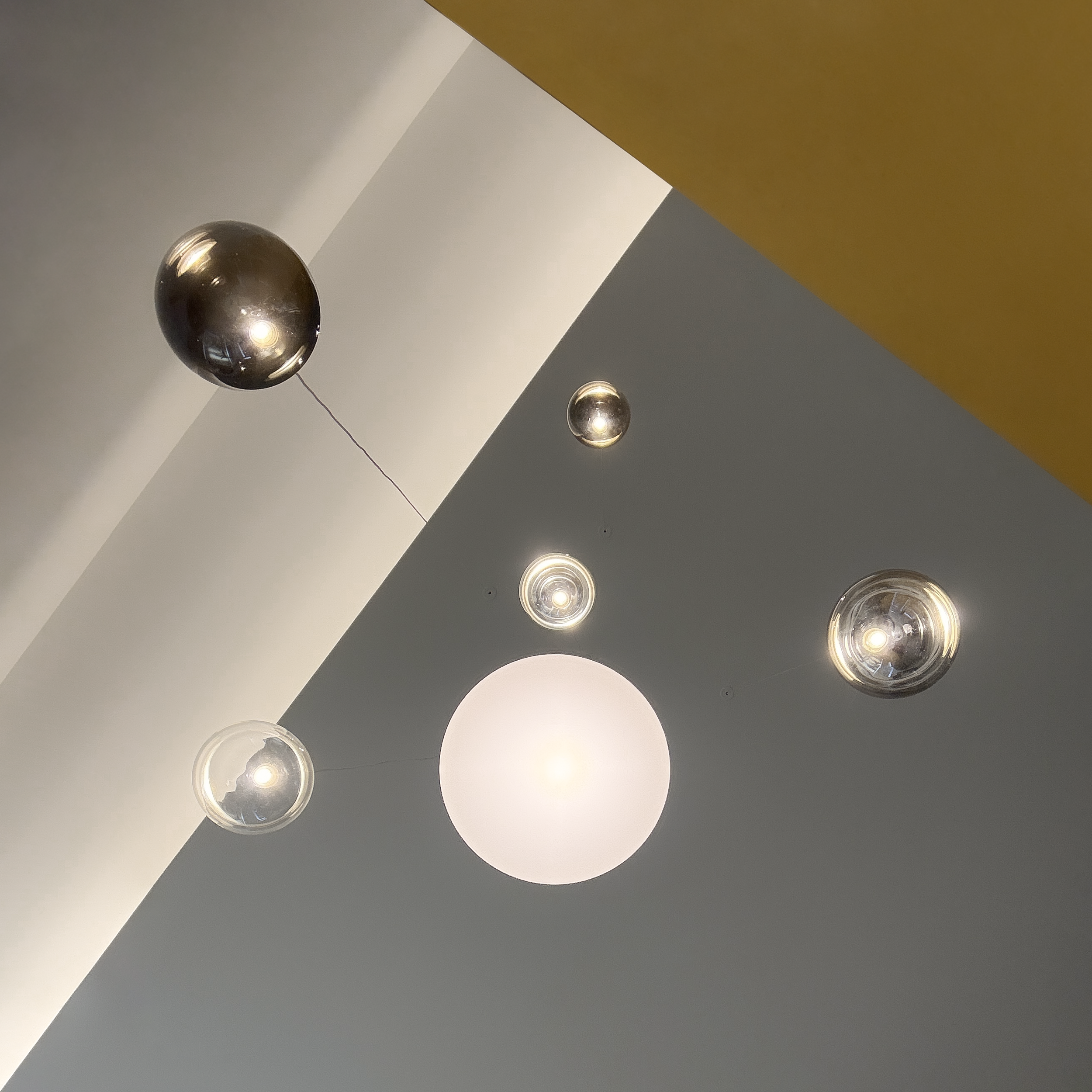 Dettaglio dei corpi illuminanti sospesi della serie Random Solo di Lodes e del setto colorato giallo, Farina Loft, Cagliari