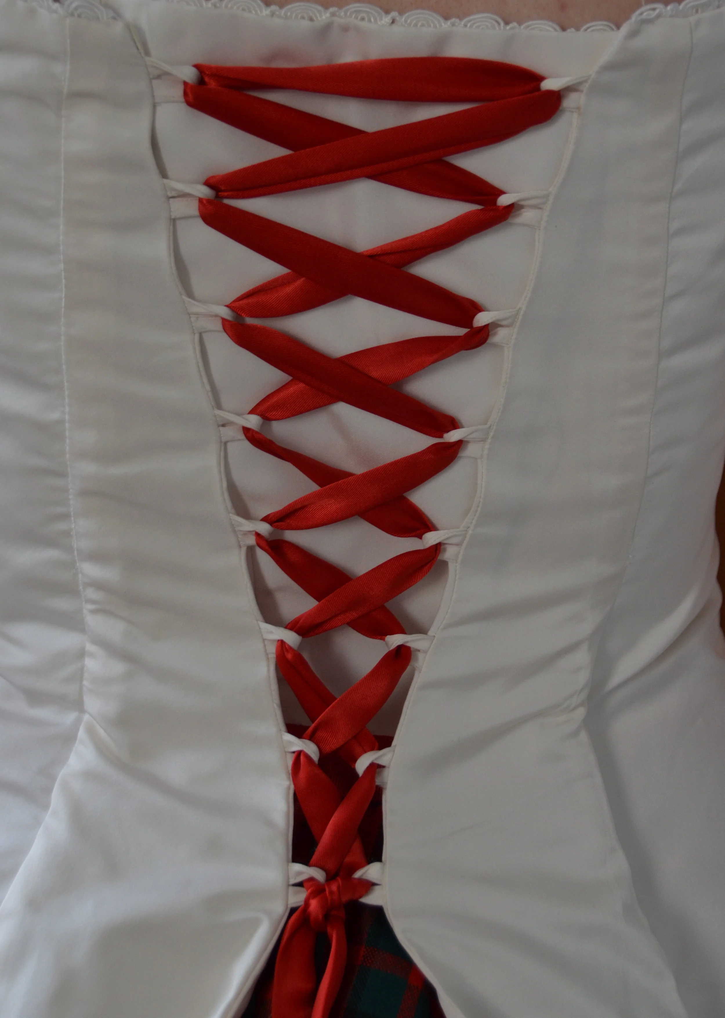 Looped corset back with red satin ribbon ties.