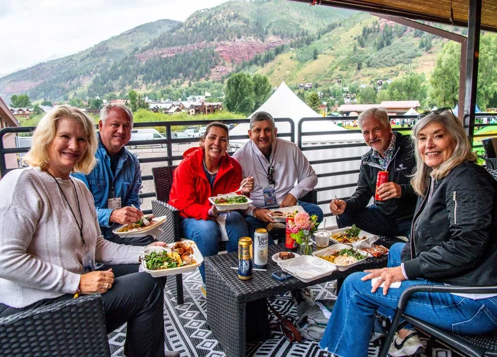 Society Club ticket holders relaxing in the exclusive side-stage lounge at Telluride Jazz Festival, enjoying premium hospitality, comfortable seating, food and drinks, and close-up views of live performances.