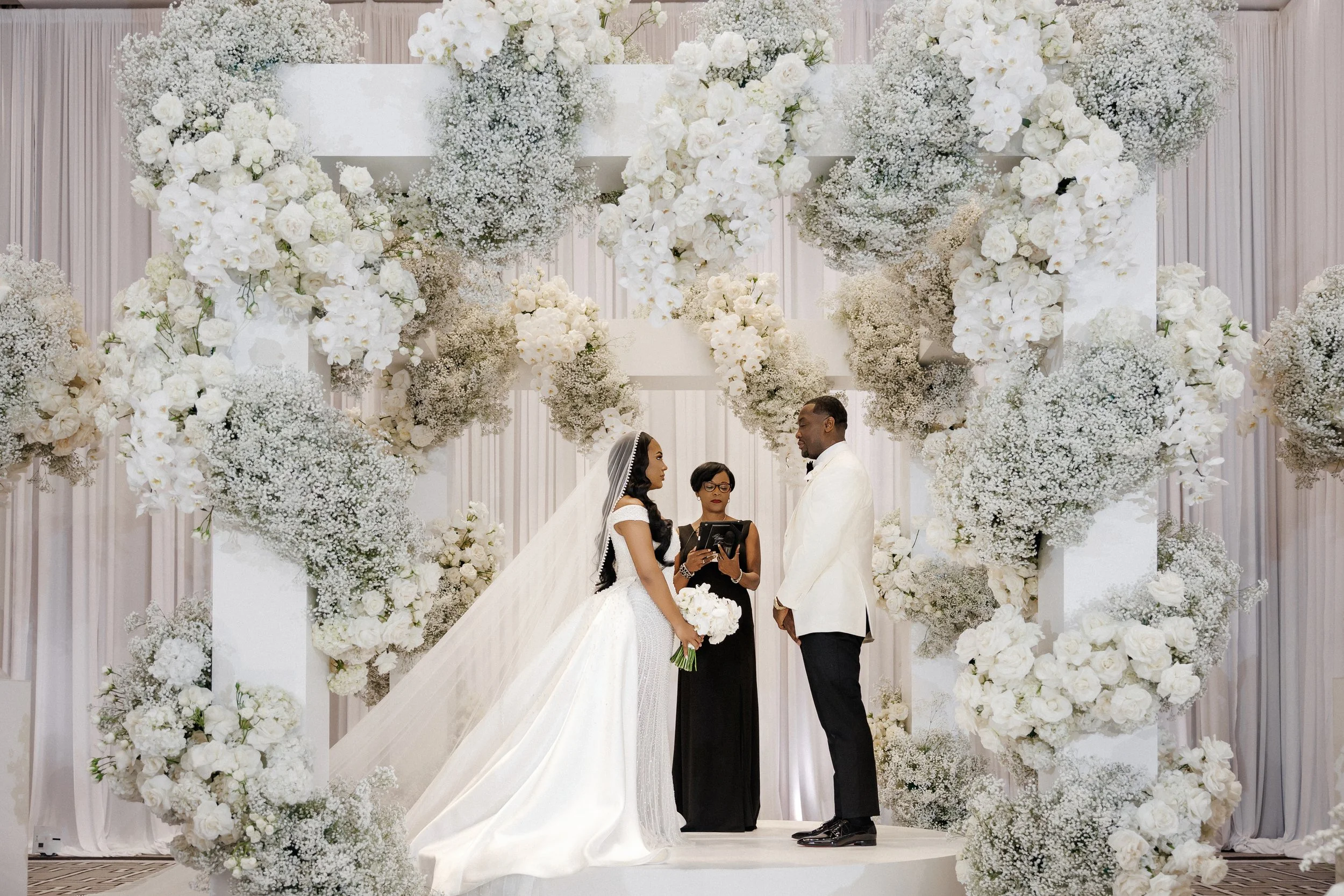 Officiant Desiree Dent with a couple under a gorgeous floral arch at The Langham Chicago.