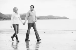 Couple walking on beach holding hands smiling
