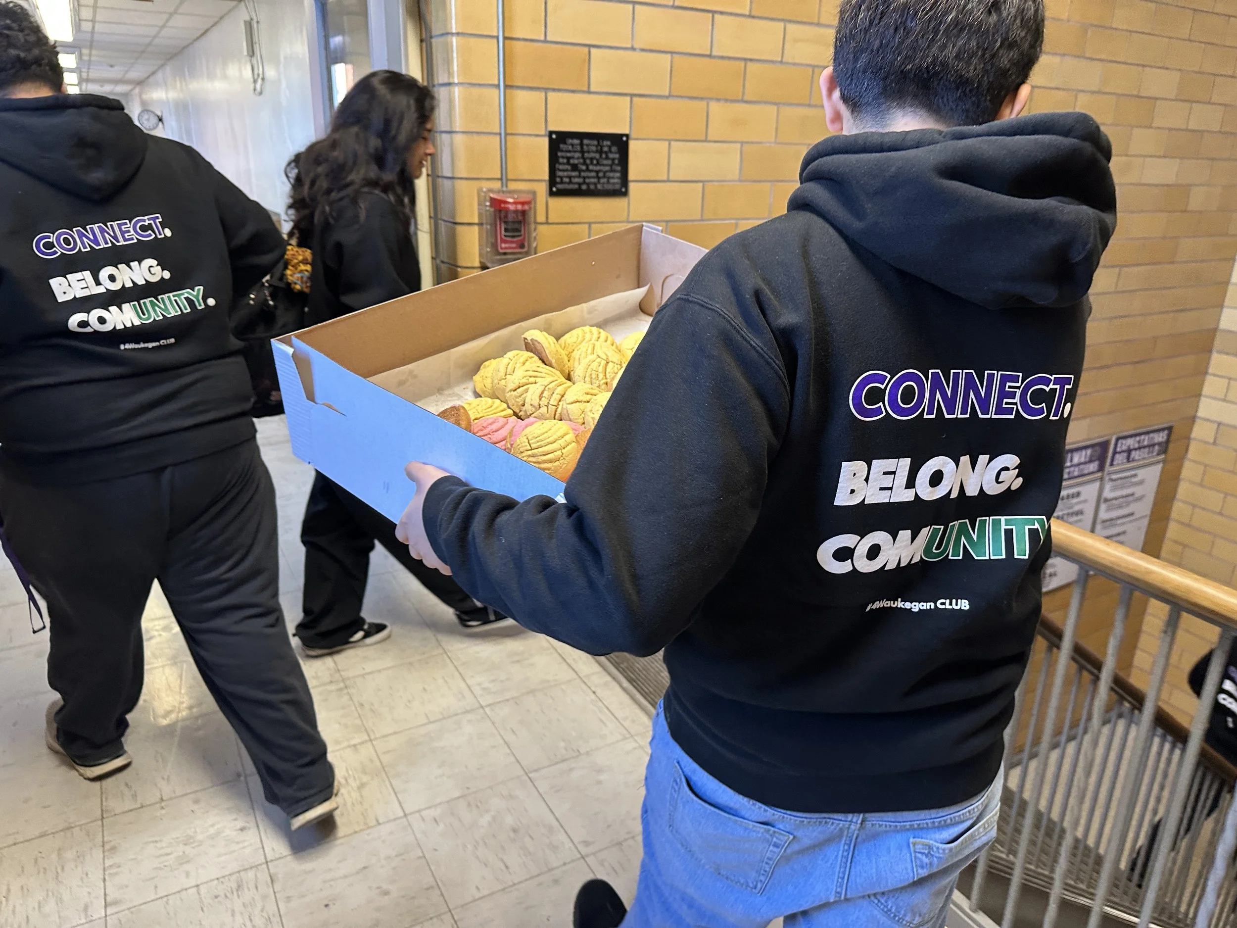 A group of people wearing matching hoodies with the words 'CONNECT. BELONG. COMMUNITY.' printed on the back.