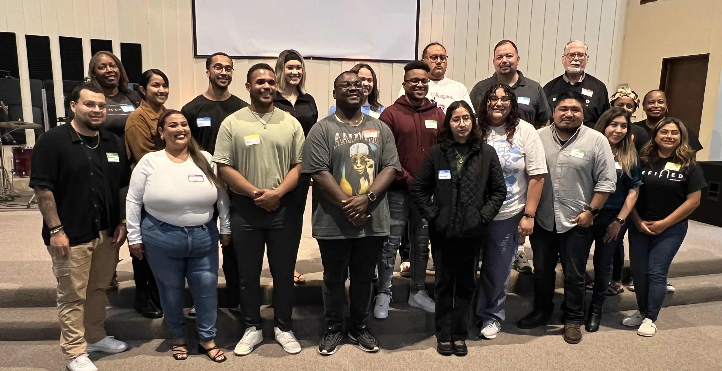 A group of 20 diverse people standing together in a conference room.
