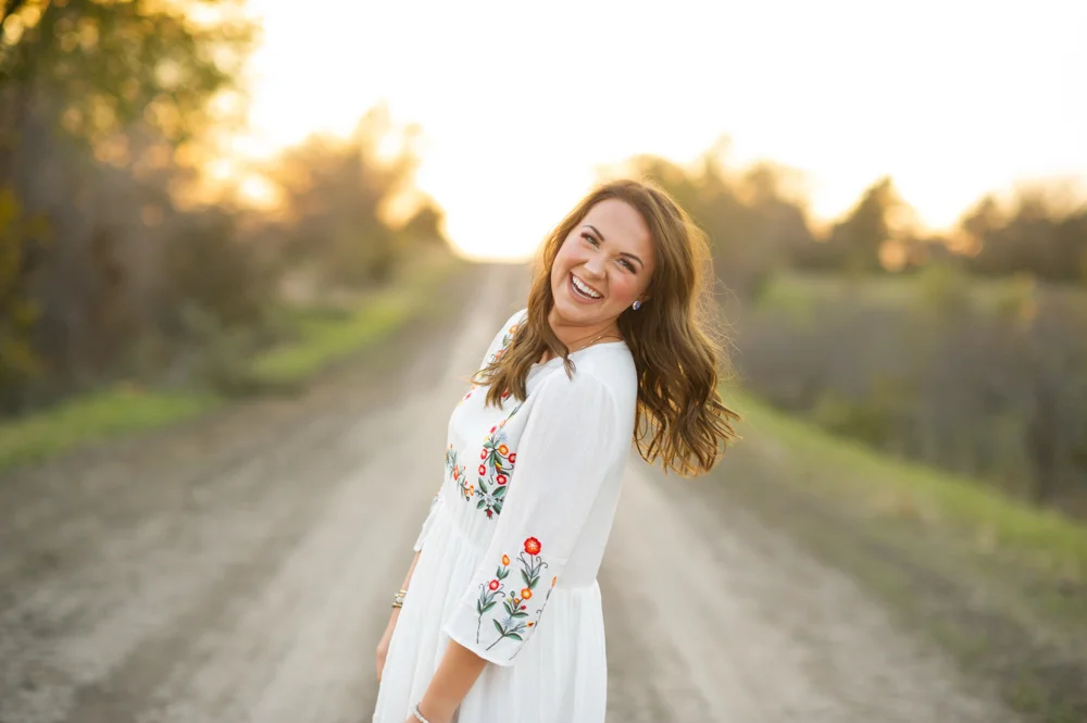high school senior girl portrait photographer in dorchester nebraska photos of breanna zoubek of wilber nebraska with flowers, streams, sunset, tall grass, dirt roads, sun dresses, fall leaves, and trees