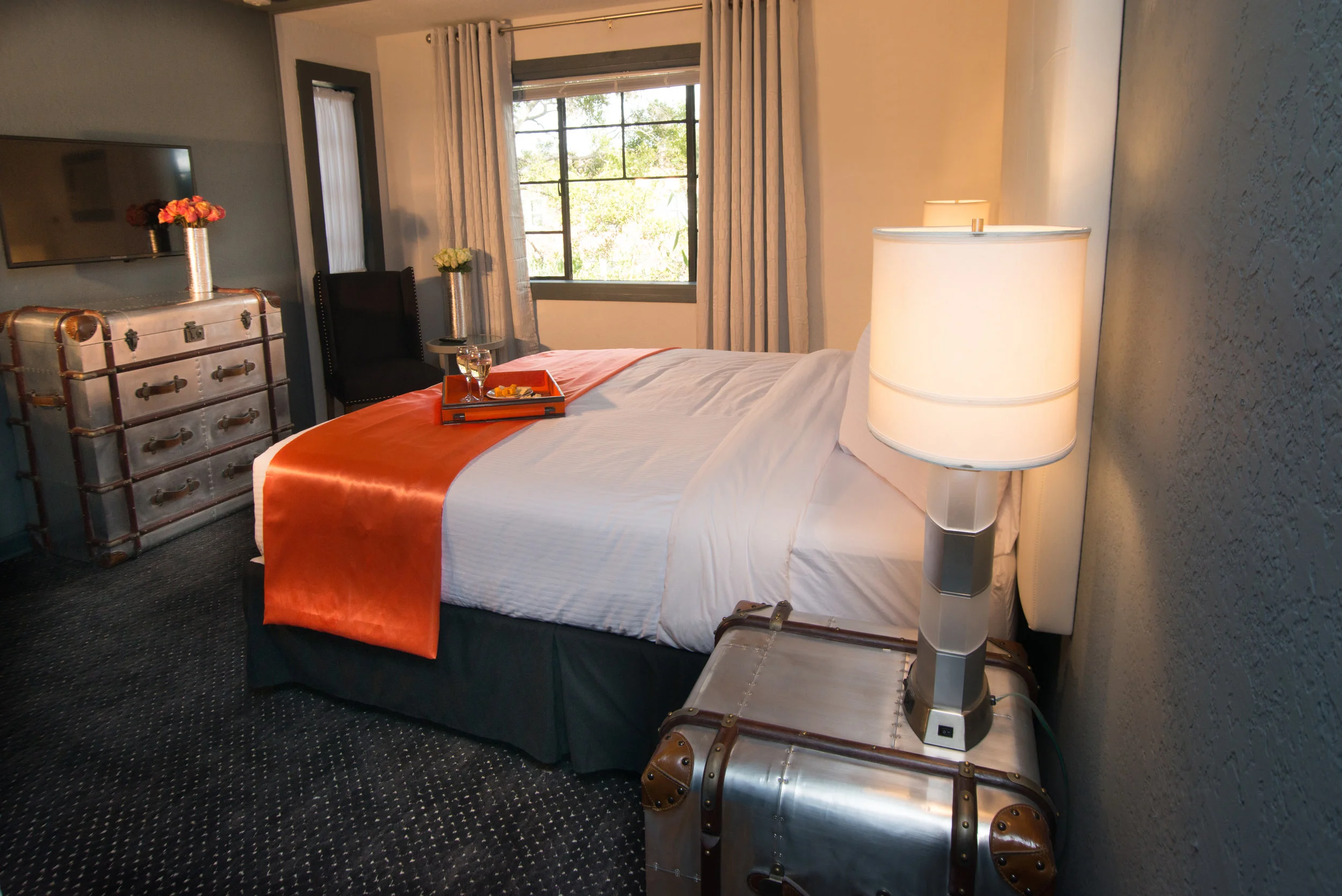 Avalon Hotel Bedroom With White Sheets and White Plush Pillows with Breakfast Tray with Two Wine Glasses