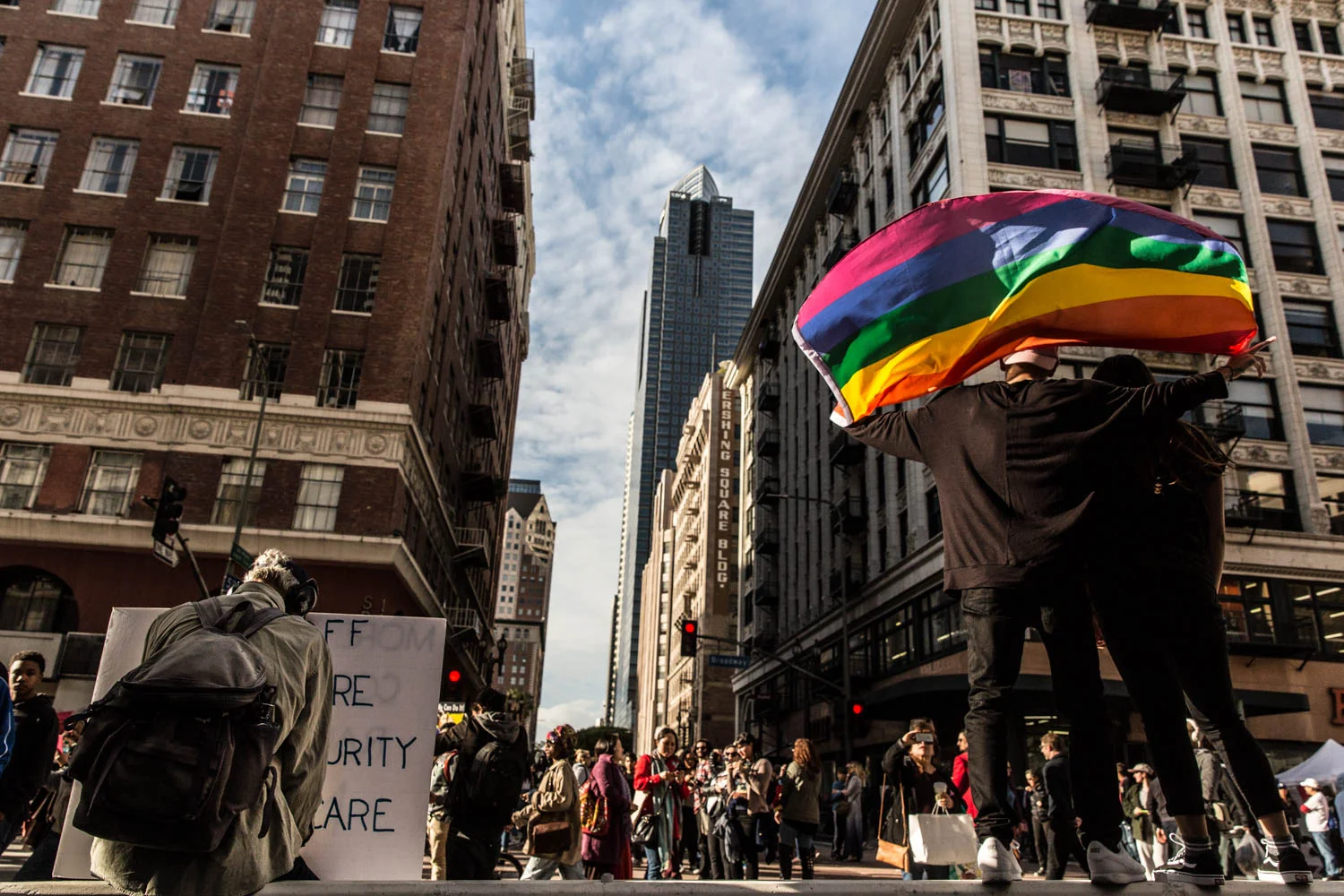 A man raises a rainbow flag- a symbol of LGBT rights- during the Women's March. An elderly man rests with his political sign. Over 750,000 people gather in downtown Los Angeles, Los Angeles, Calif. to attend the Women's March. Citizens carry colorful signs, wear pink Pussy Hats, and call for awareness and improvement of gender, racial, sexual equality. The event is attended by both men and women the day after Donald Trump's presidential inauguration and is mirrored worldwide in over 600 cities; 673 were official sister cities, with an estimated 4.9 million participants . Jan. 21, 2017