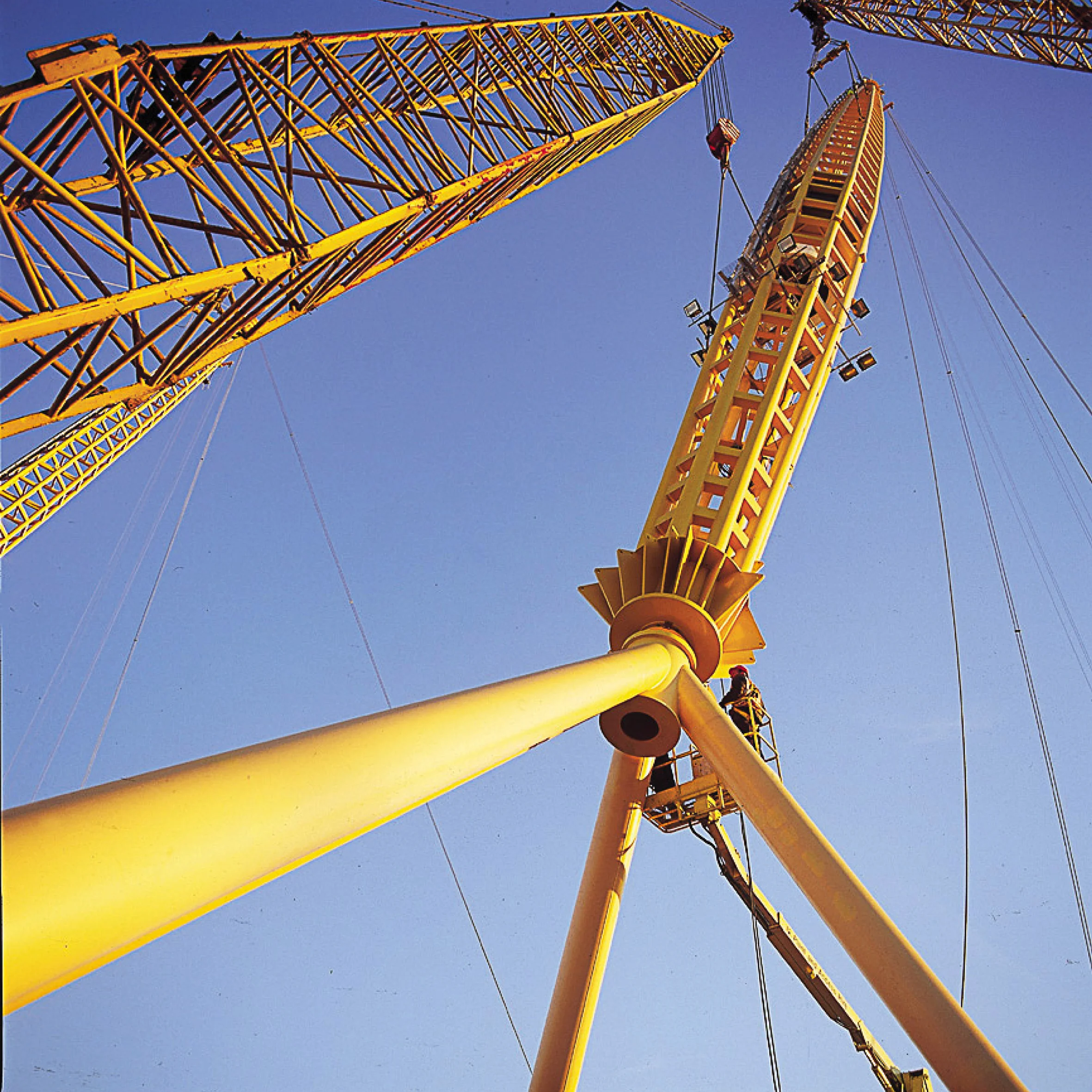 Under construction photograph of the yellow steel pylonds being raised into position to form the structure of the Millenniumk Dome.