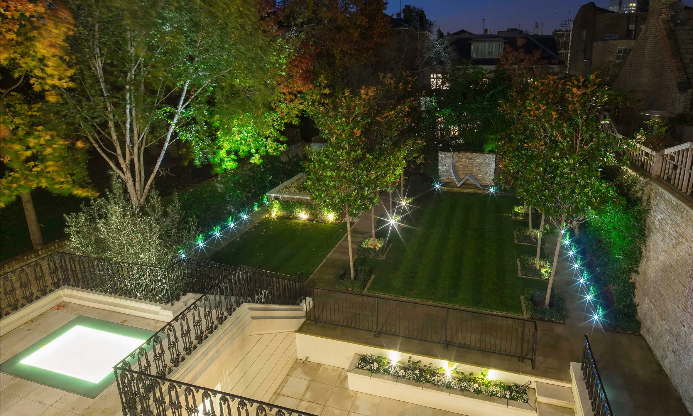 Night time photograph of the landscaped garden above the underground swimming pool.