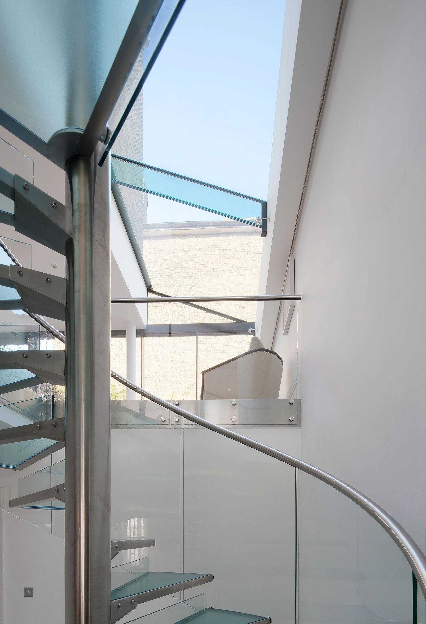 Detail of the glass and steel staircase. View to the living space with modern glass roof extension