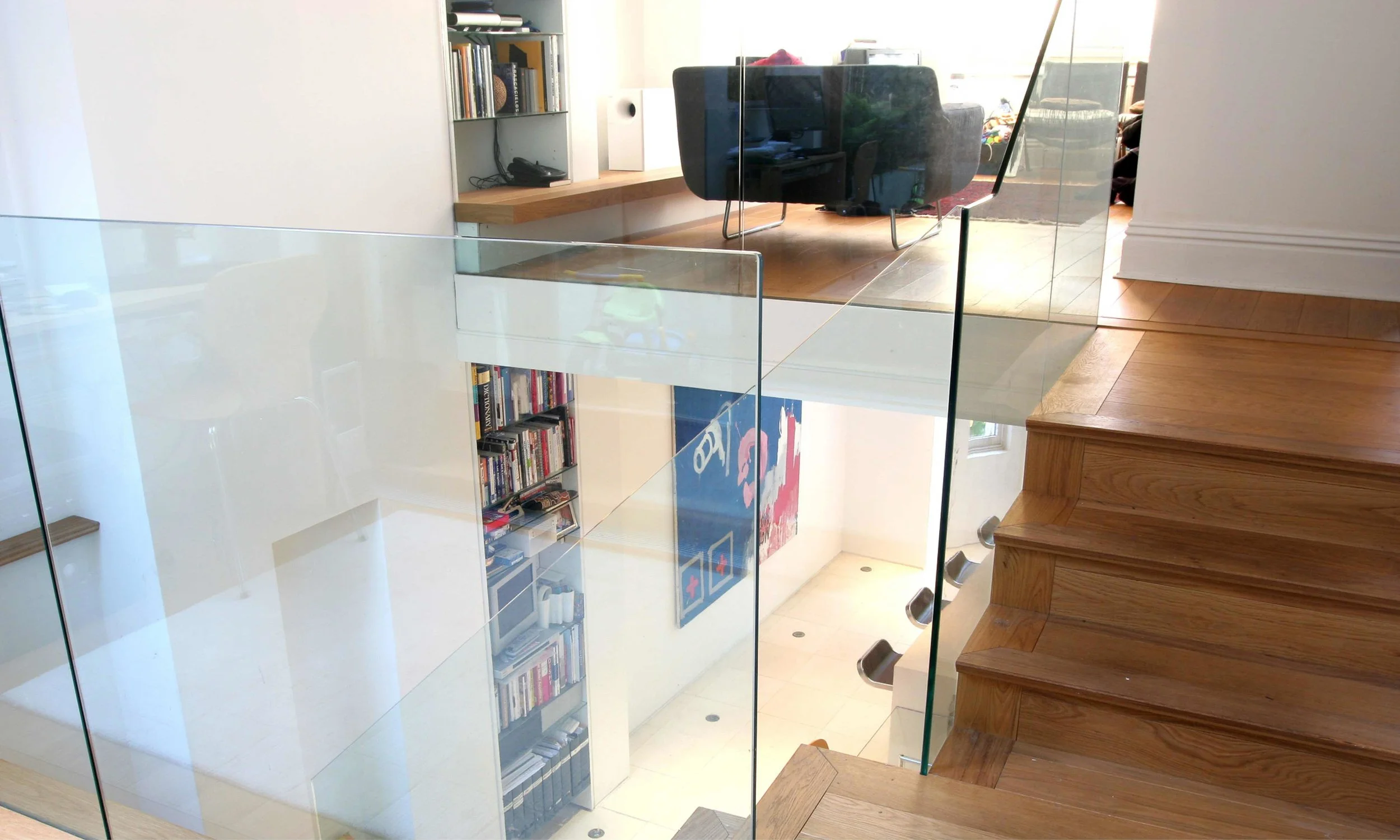 Detail image showing the frames glass balustrades that surround the staircase. These allow natural light to flow down through the living and dining spaces down into the kitchen,