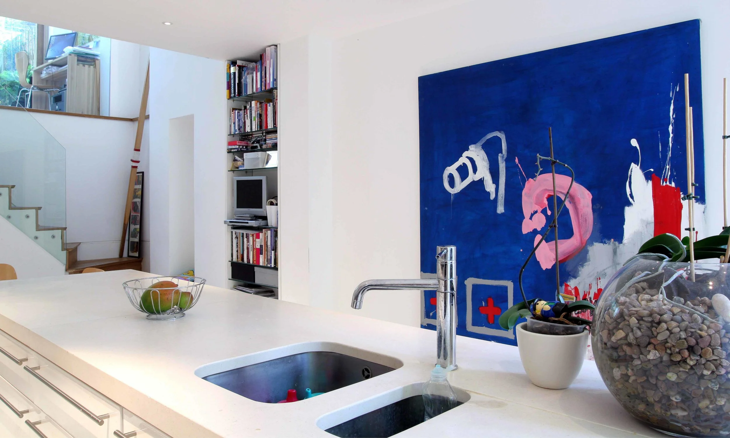 The new kitchen in the basement of the property. The glass __ to the staircase brings additional light to allow the space be naturally light. Modern art hangs on the walls bringing colour to the space.