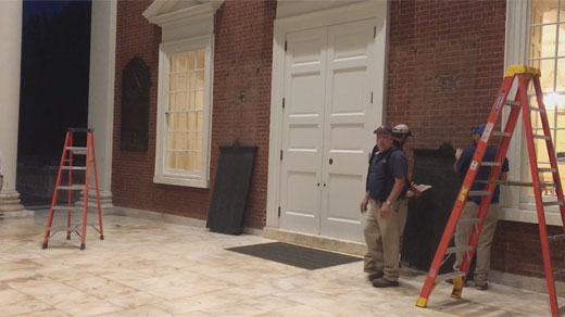 Workers pry Confederate plaques off the Rotunda's facade. Photo Courtesy Daily Progress.