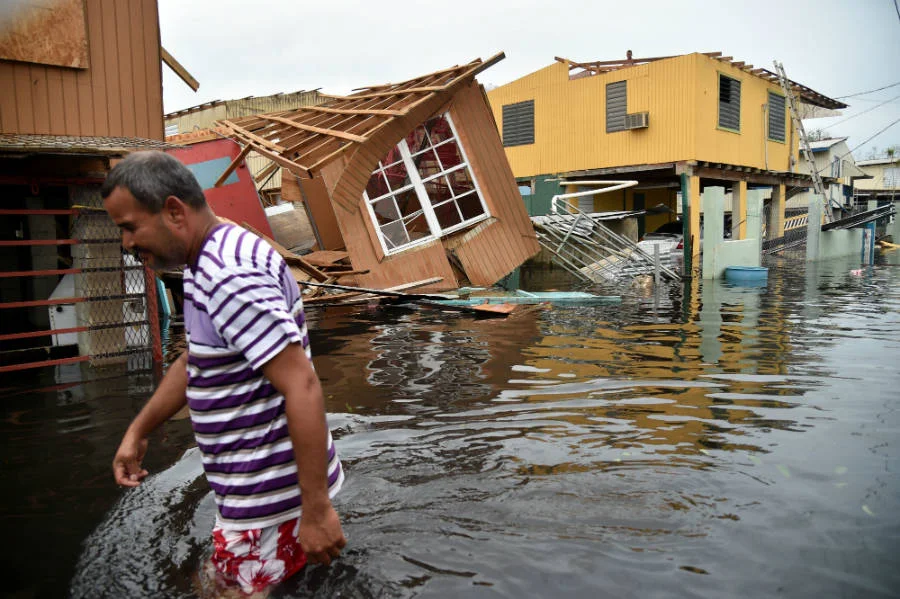 Puerto Rican resident wades through flooded street after Hurricane Maria. Photo courtesy of Hector Retamal/AFP/Getty Images.