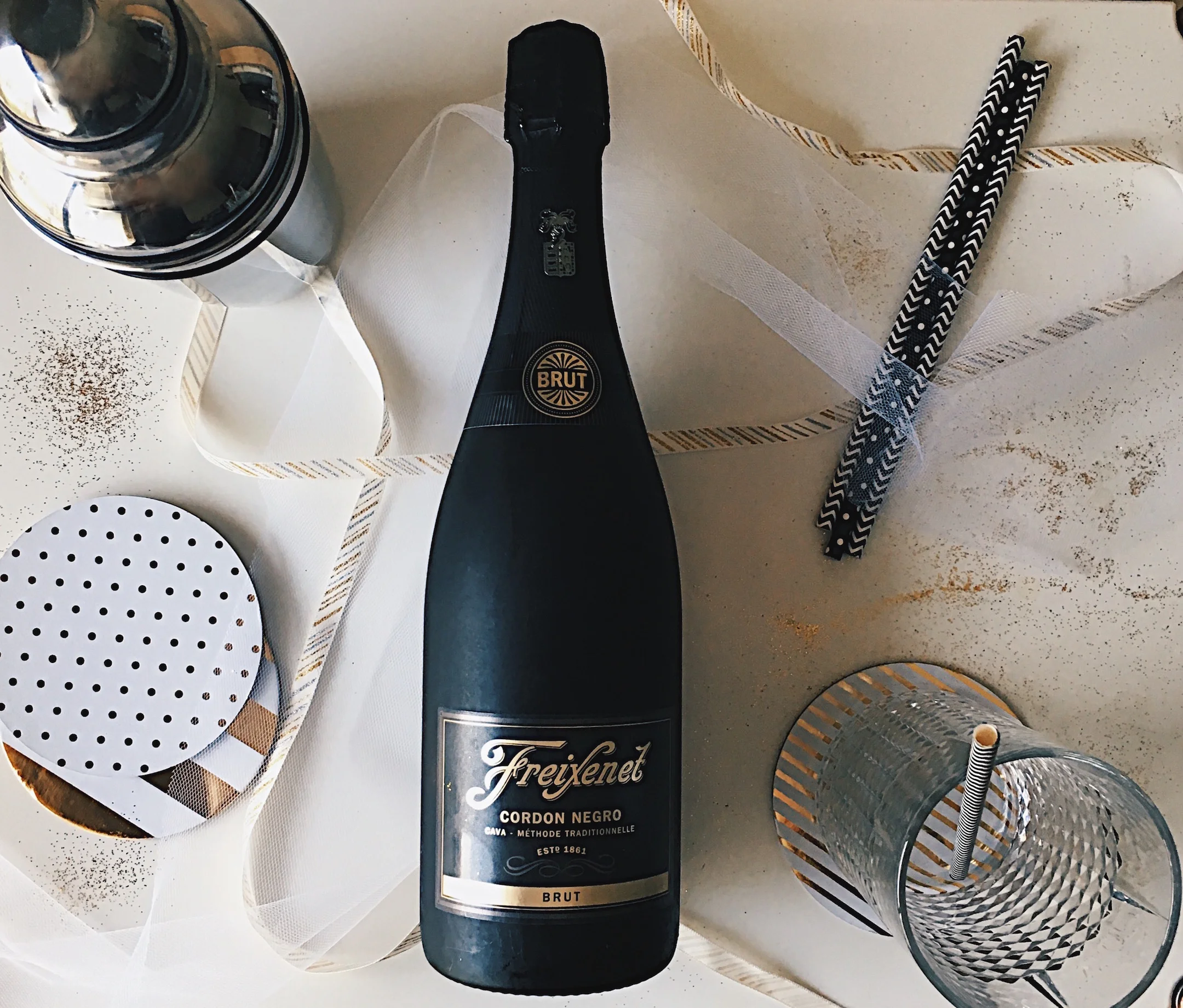 Freixenet Cordon Negro Brut Champagne/ Gold glitter table setting/ Black and White Paper straws/ silver shaker 