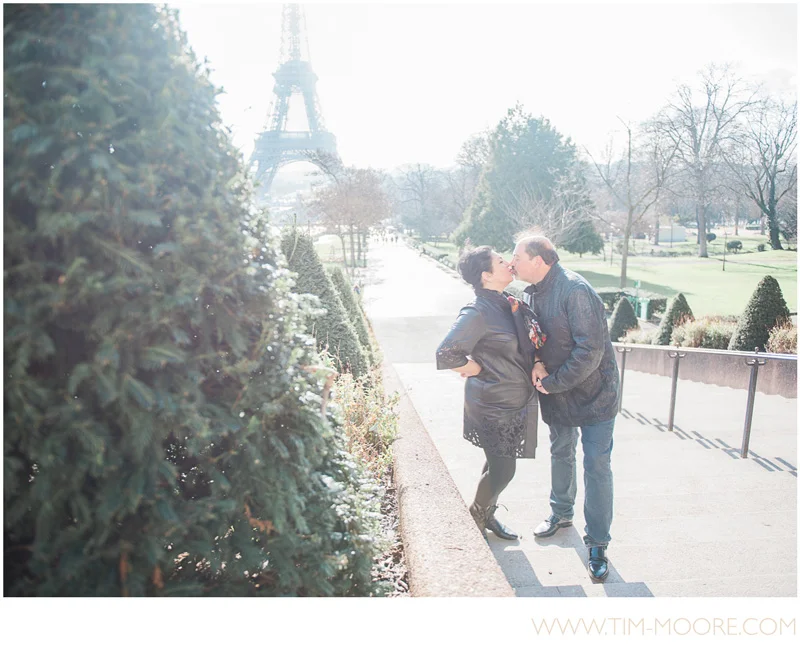 A very cute couple kissing in front of the Eiffel Tower to celebrate their eternal love