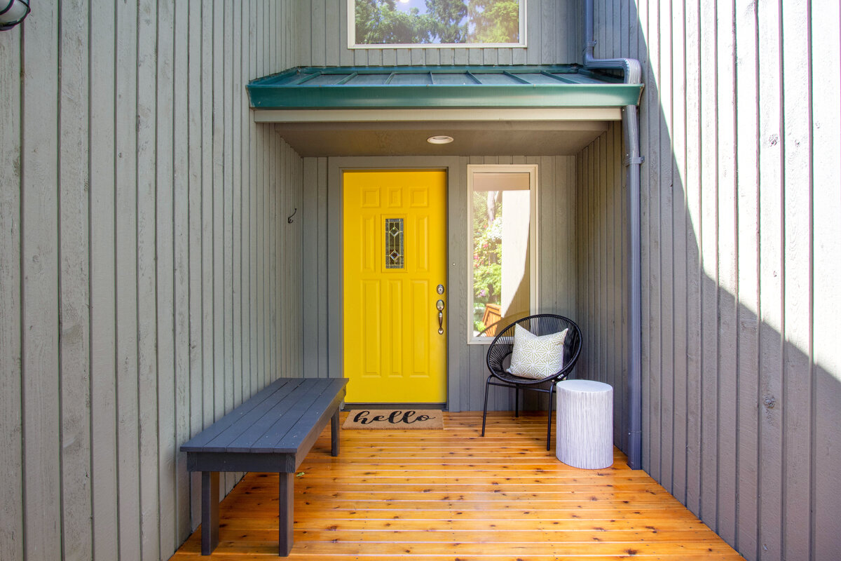 The bright yellow doorway welcomes you into the cozy interior of this serene home. 