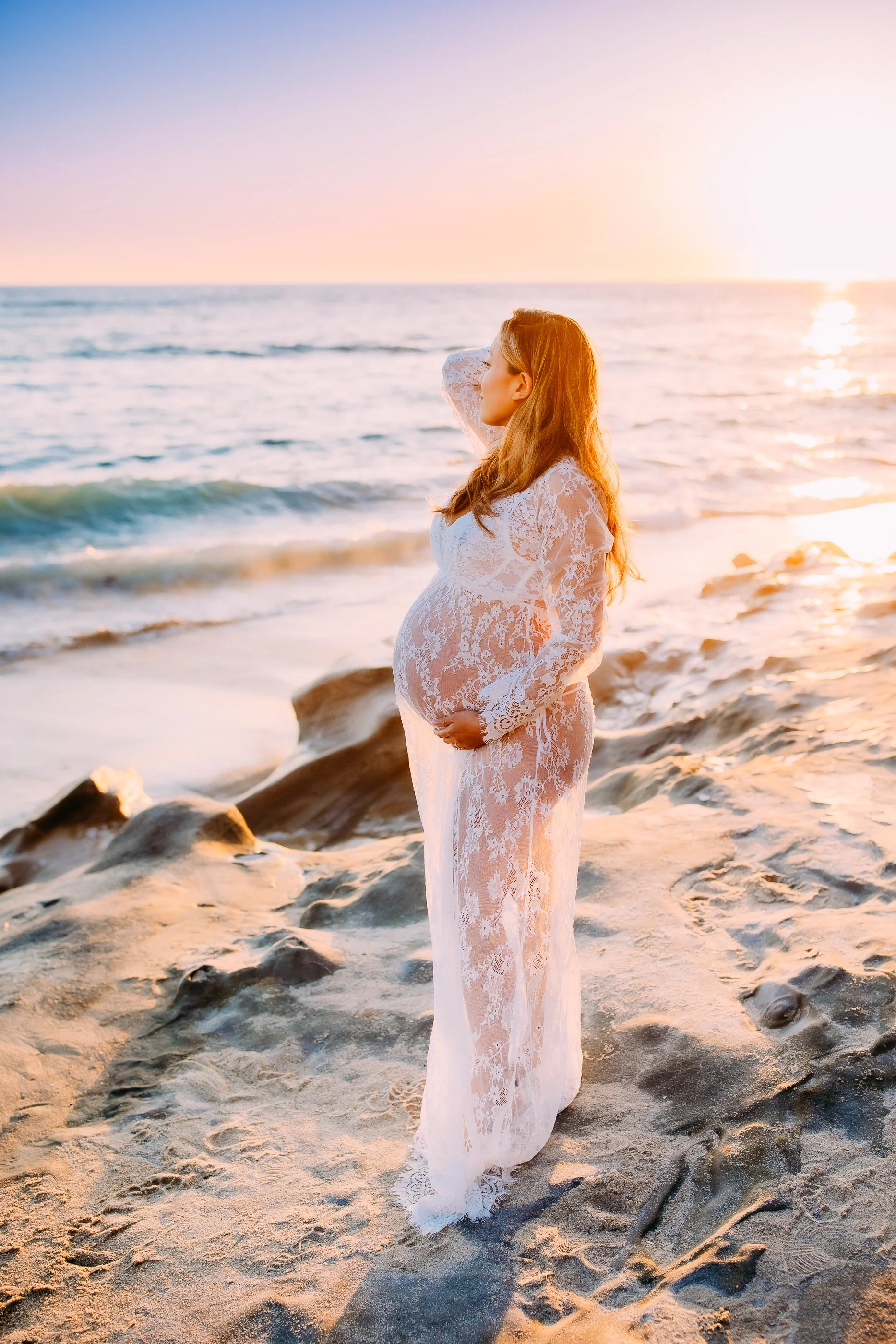 pregnant woman gazing out at the ocean during her Laguna Beach sunset maternity photo session