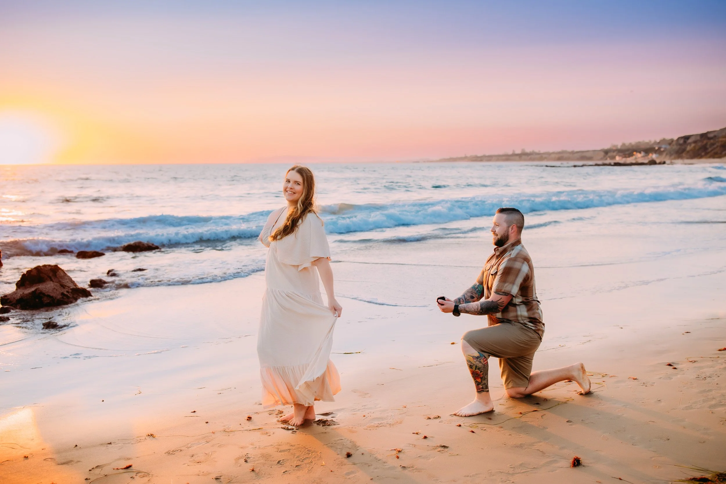 man doing a surprise proposal to his girlfriend during their photo shoot at sunset in Newport Beach, CA