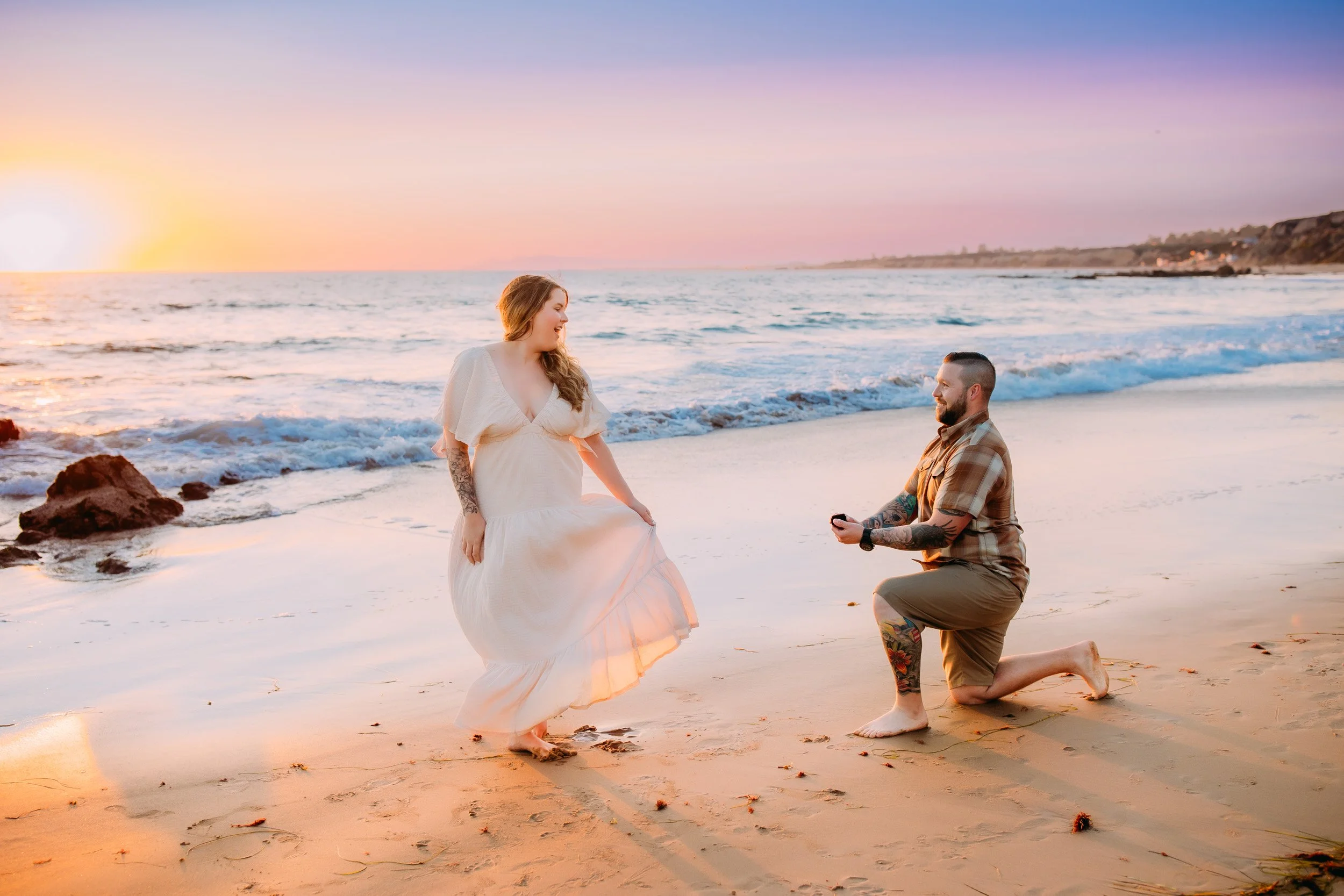 man doing a surprise proposal to his girlfriend during their photo shoot at sunset in Newport Beach, CA