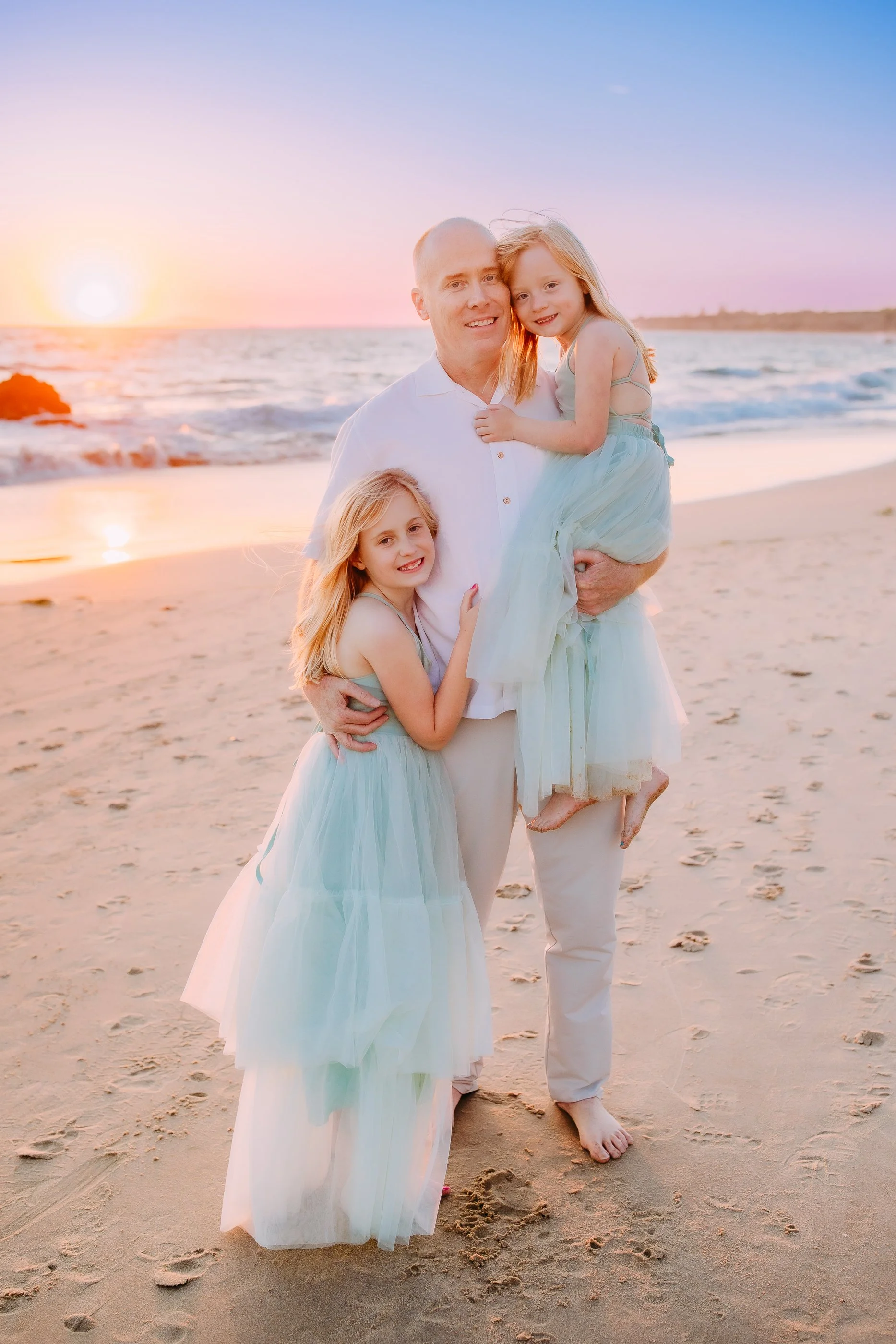 dad and his daughters posing for the camera during their beach photoshoot in Newport