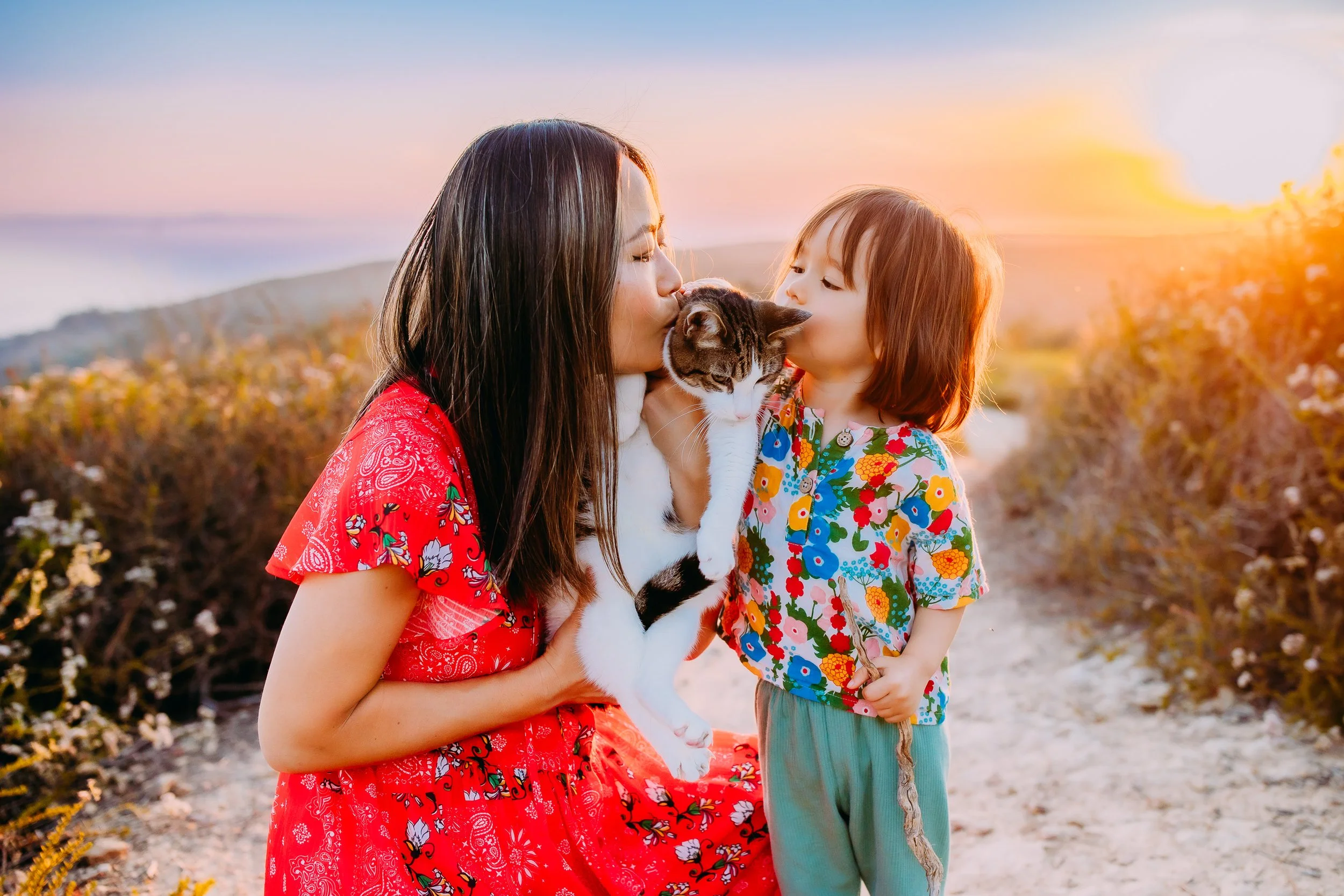 mom and son loving on their pet during their family photo session at sunset in Laguna Beach, California
