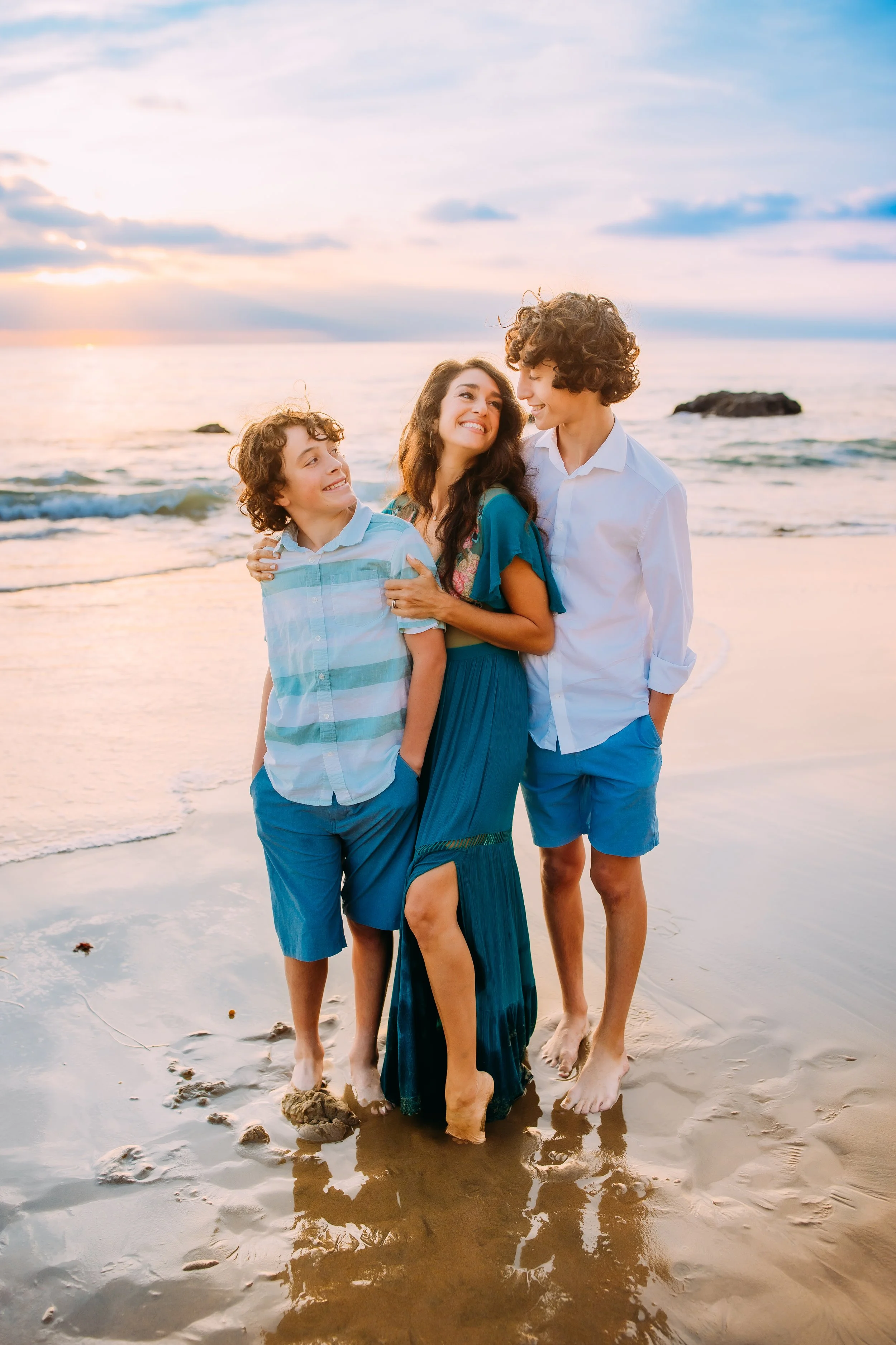 mom and her boys smiling and embracing at the beach during their family photos in Newport Beach, California