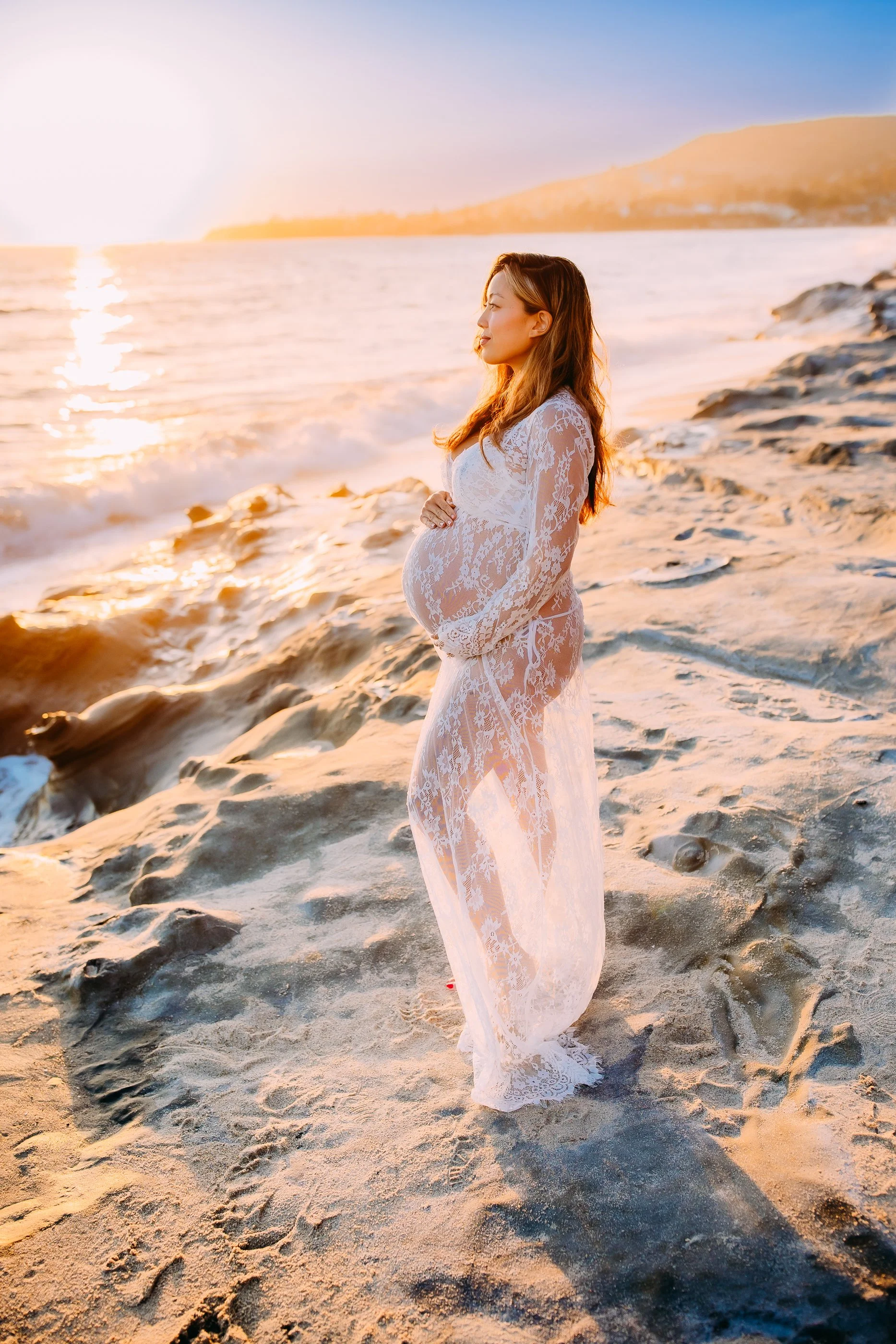pregnant mother gazing out at the sunset during her sunset photoshoot in Laguna Beach, California