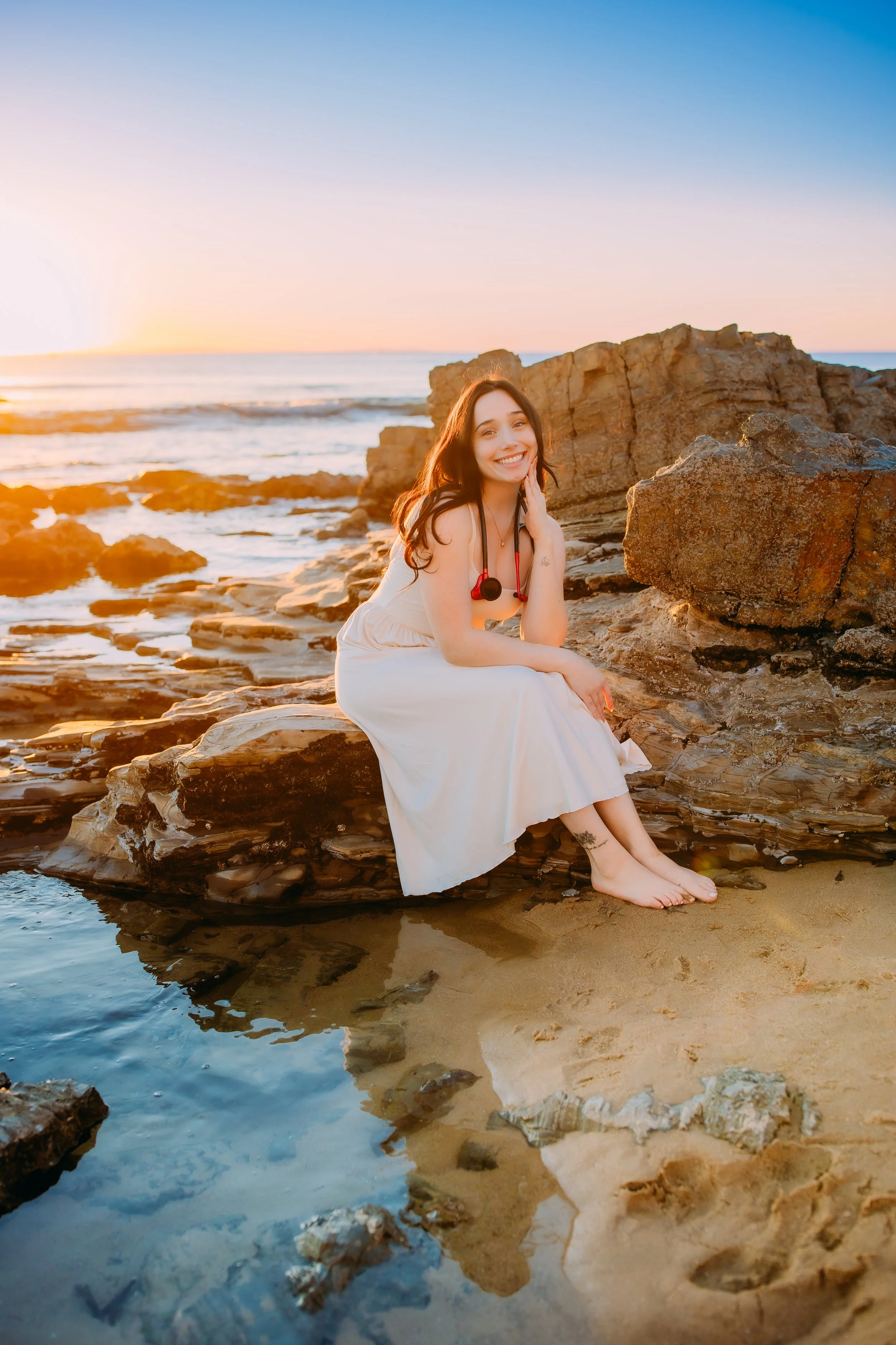 girl sitting on a rock at the beach with her stethoscope