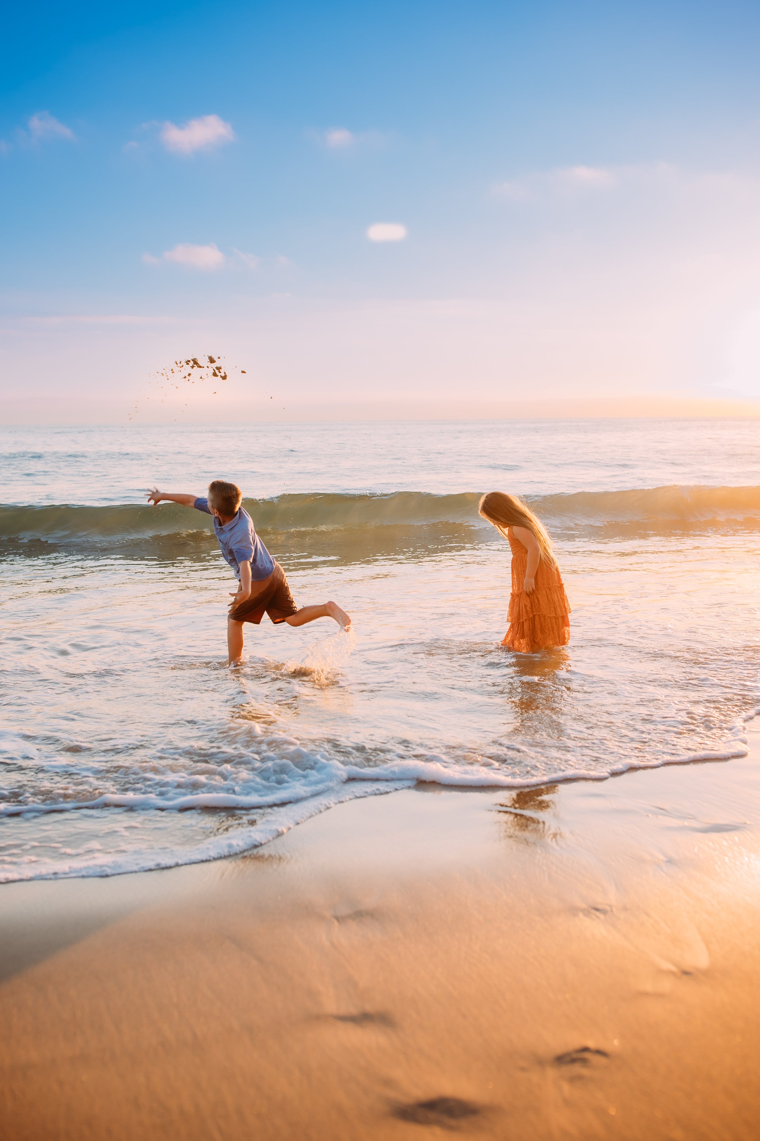 sibling playing in the water during their sunset beach photoshoot in Newport Beach, Orange County, California