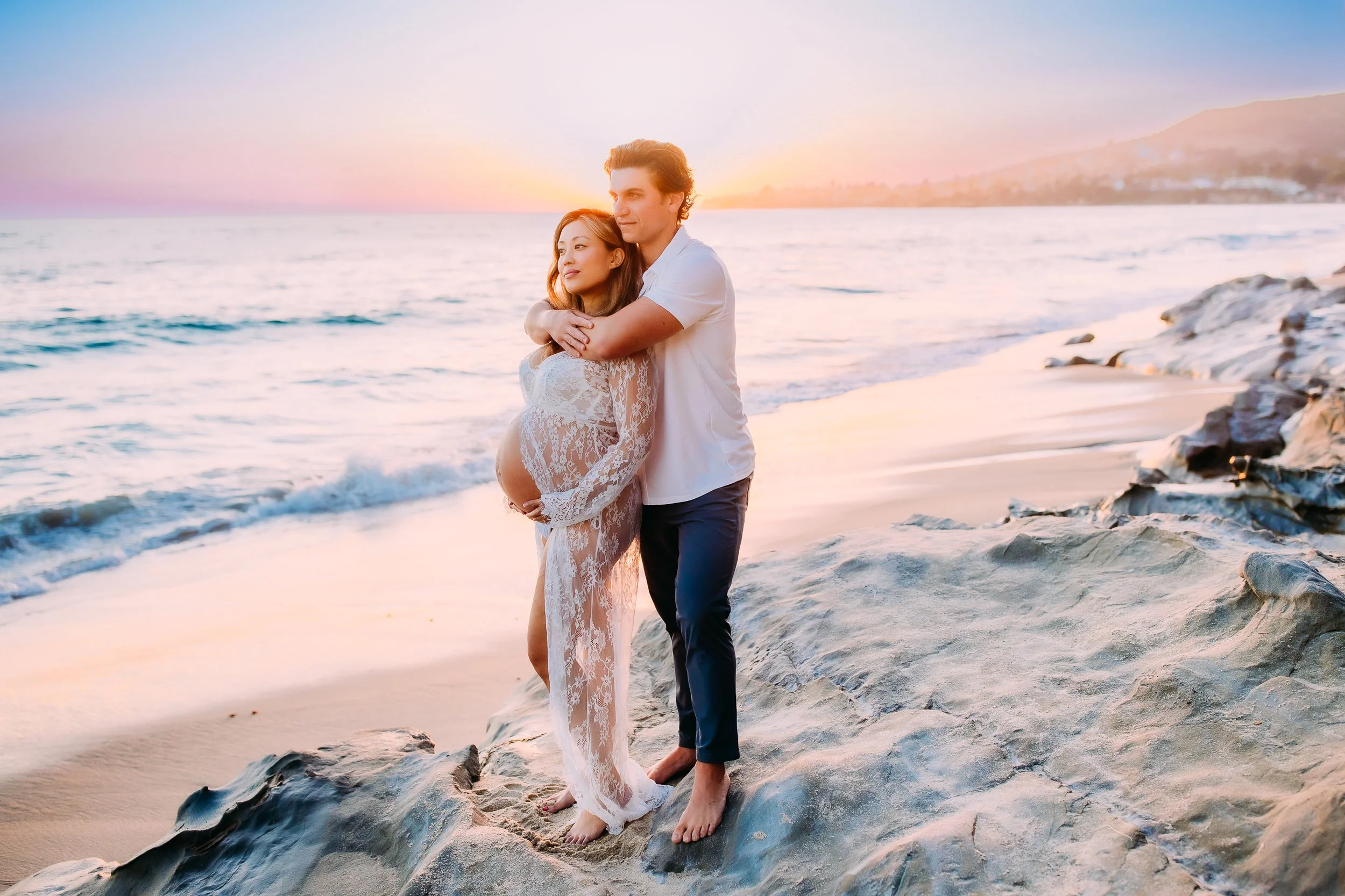 parents to be gazing out at the sunset during their maternity photoshoot in Laguna Beach, CA