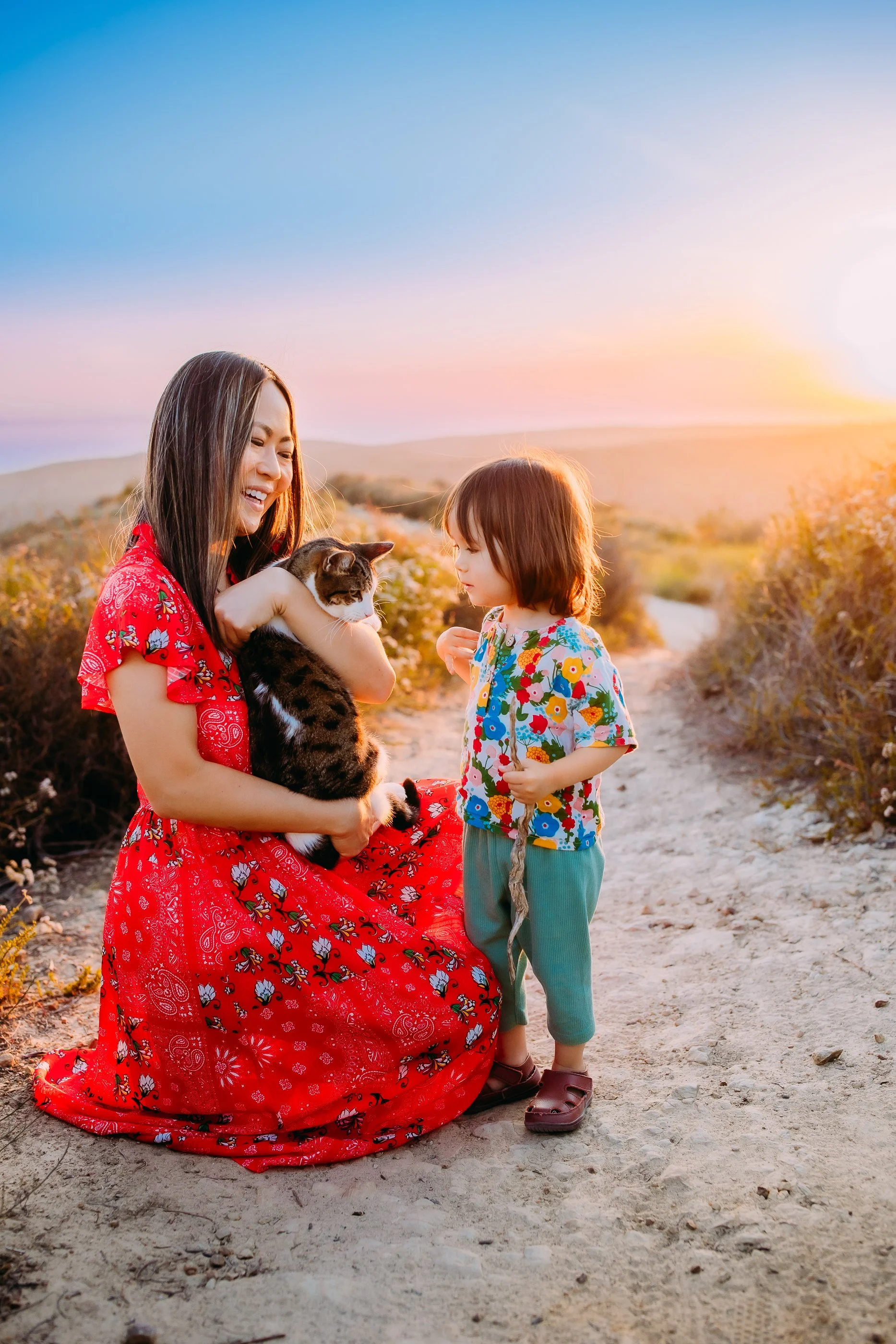 mom and son playing with their pet cat during their family photo session at sunset in the foothills of Laguna Beach, California