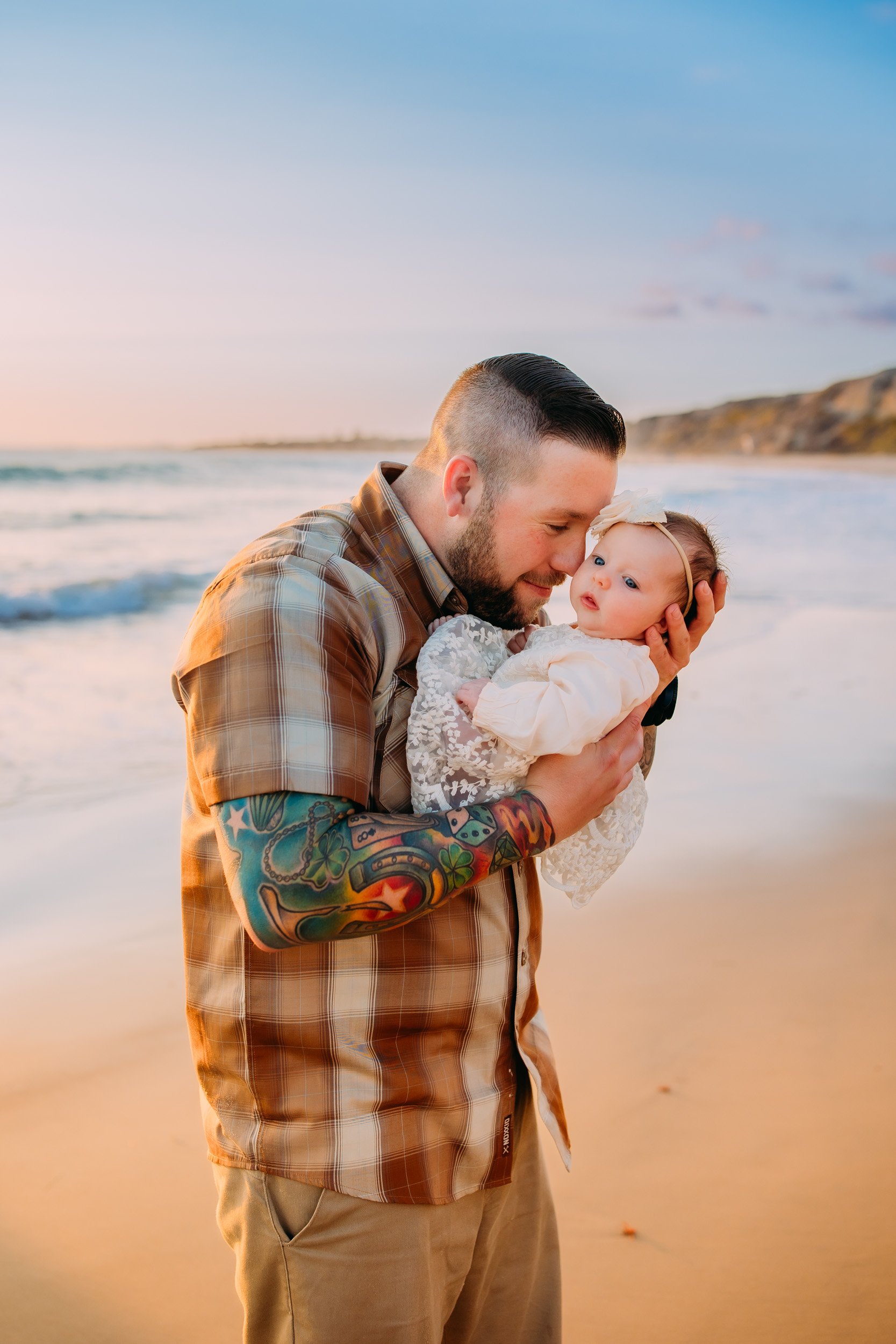 dad loving on his baby girl during their family photoshoot at sunset in Newport Beach, CA