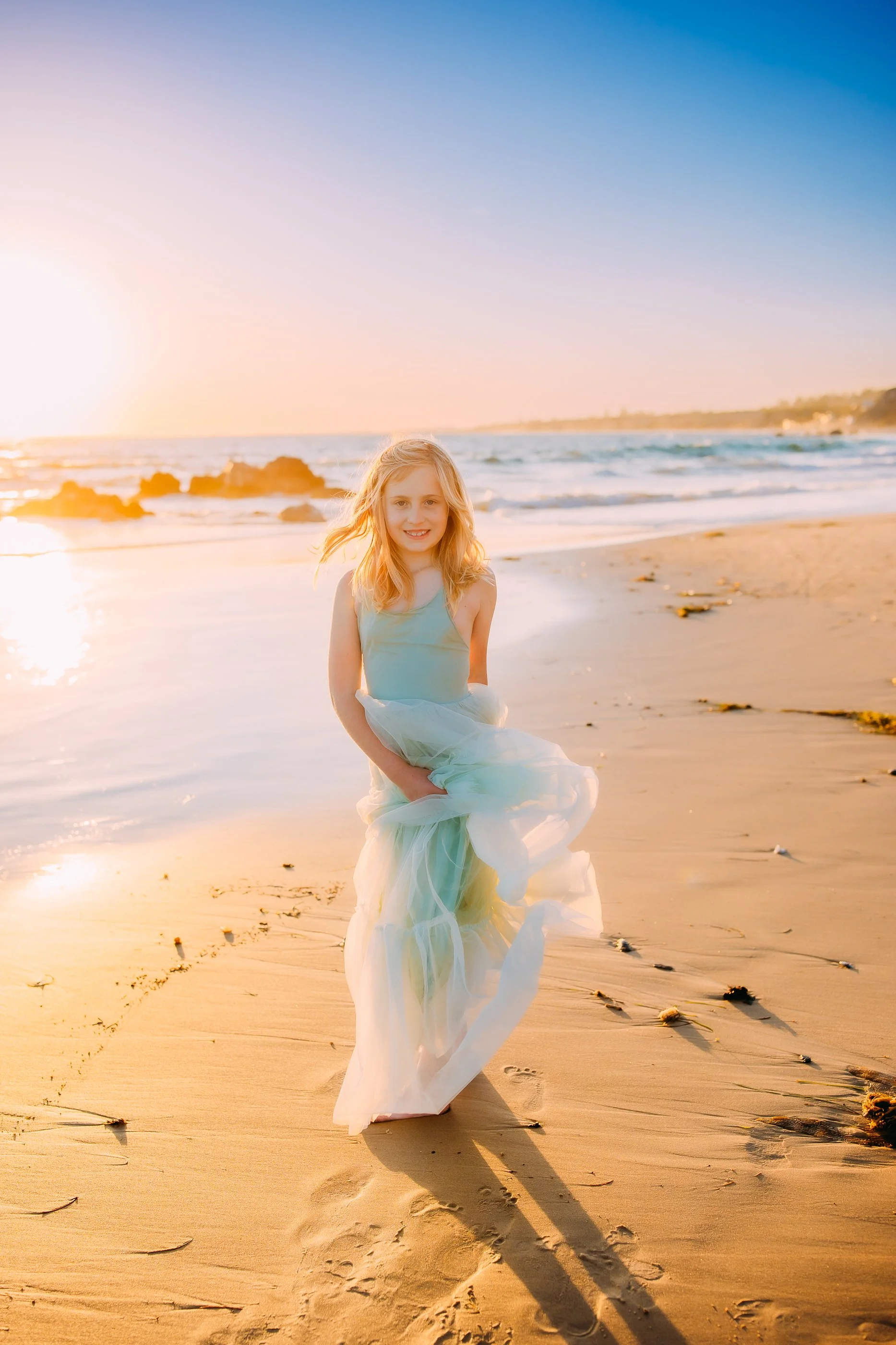 girl twirling her dress while smiling at the camera during her family photo session in Newport Beach, California