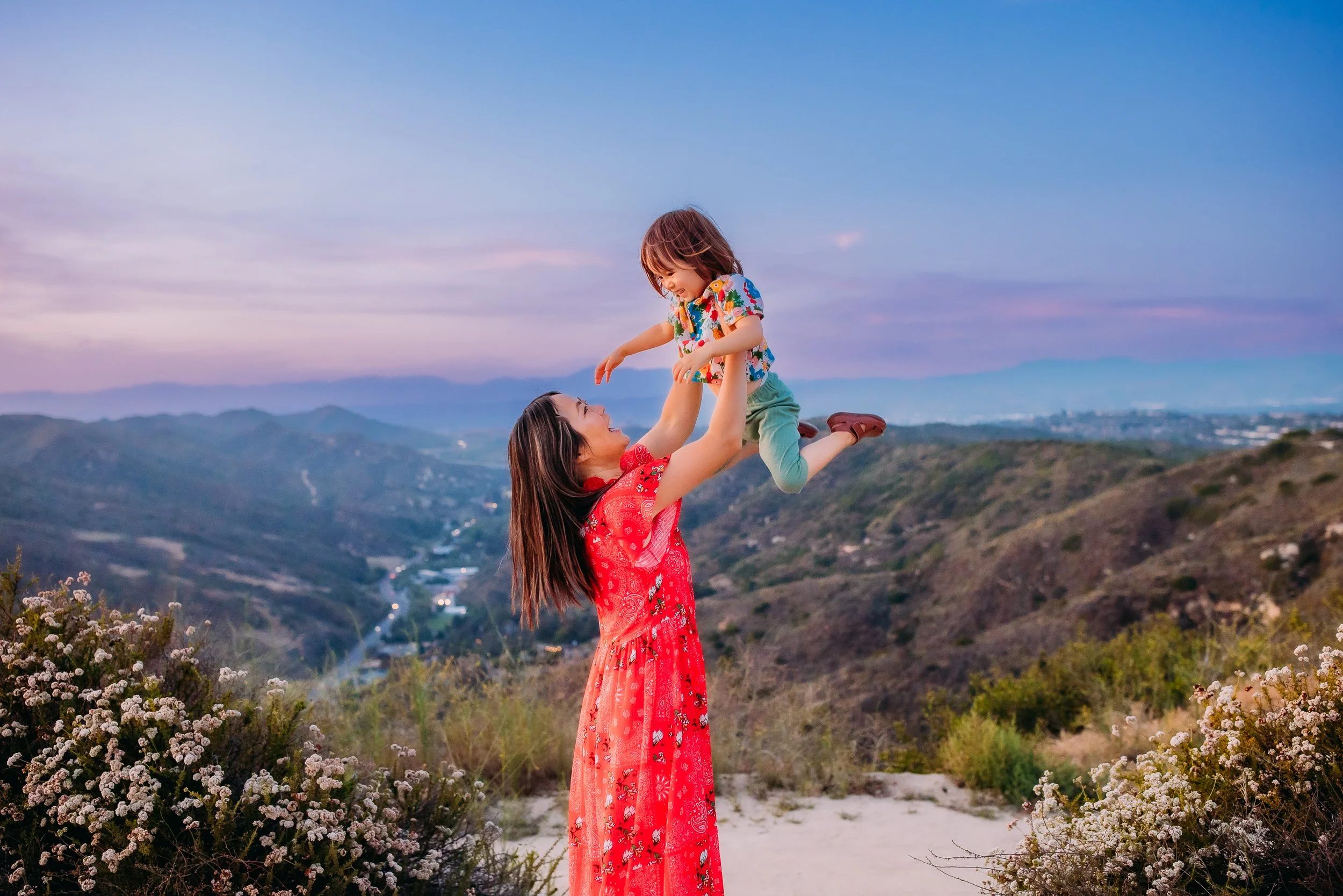 mother playfully flying her son into the air during their family photoshoot in the foothills of Laguna Beach, California